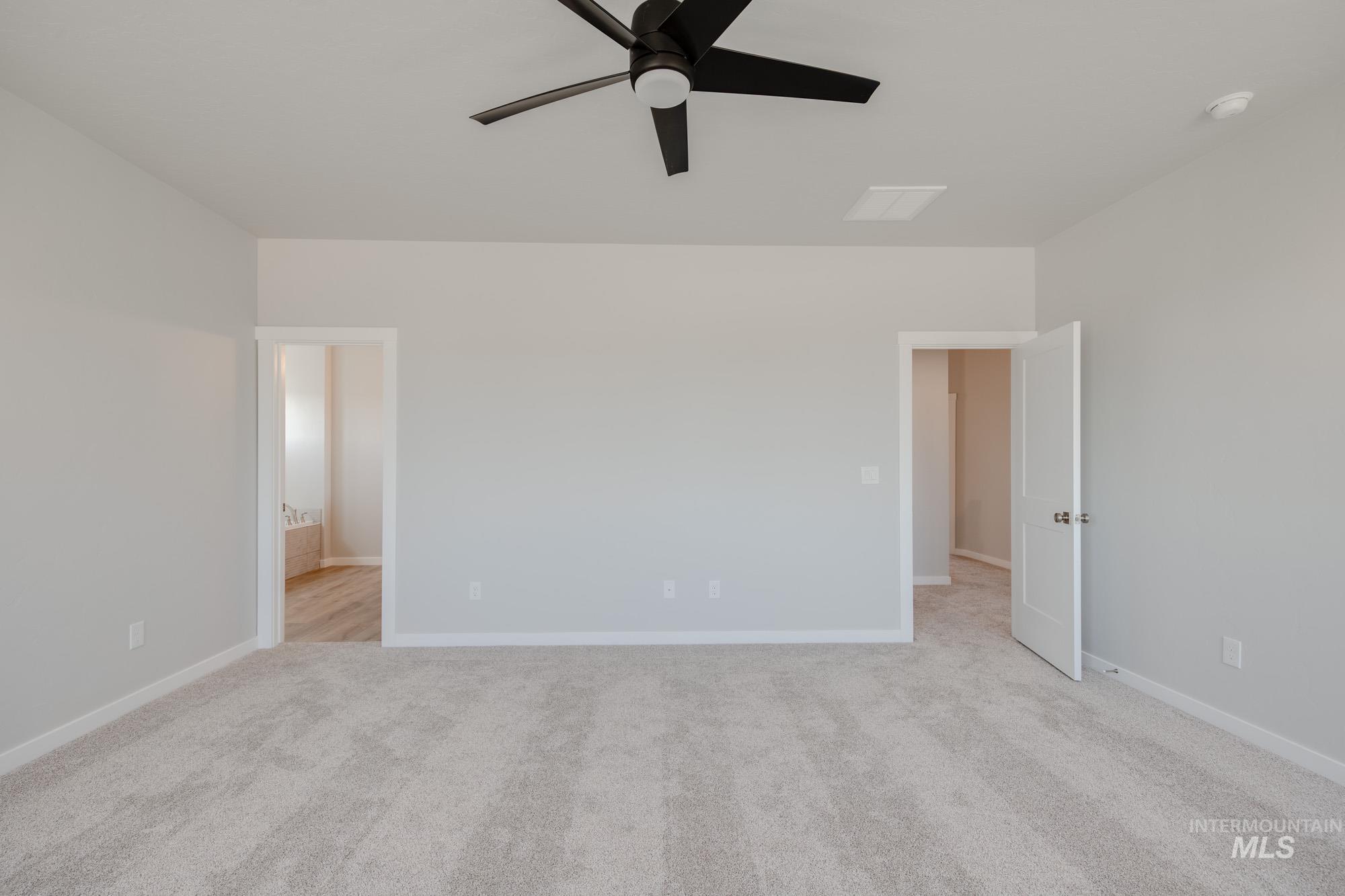 Unfurnished bedroom featuring light colored carpet, ceiling fan, and ensuite bath