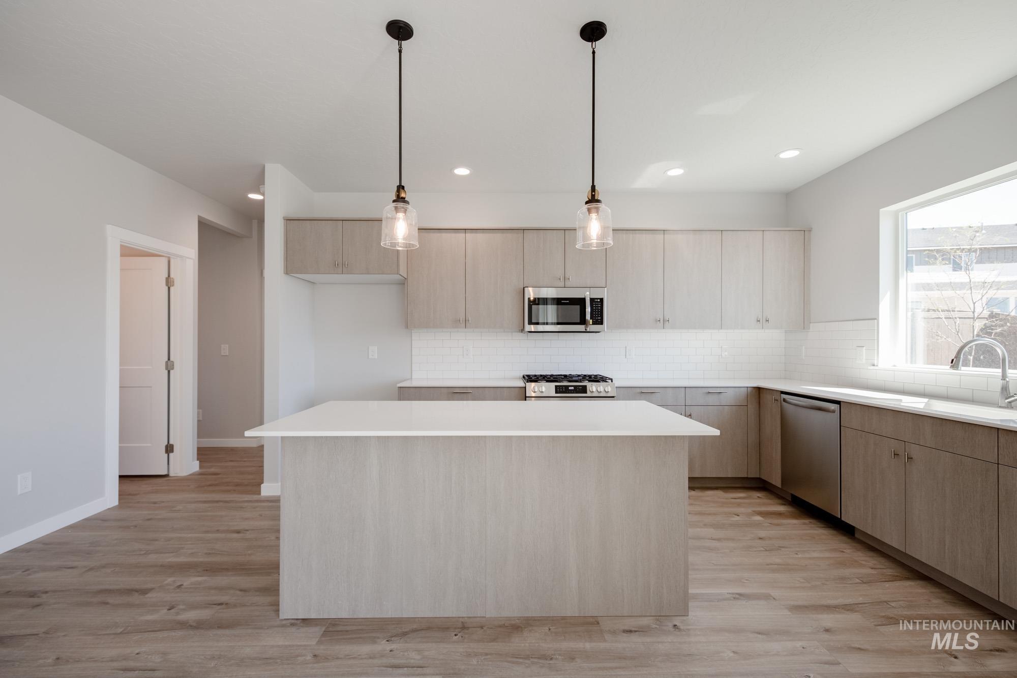 Kitchen featuring light brown cabinets, decorative backsplash, a center island, decorative light fixtures, and recessed lighting