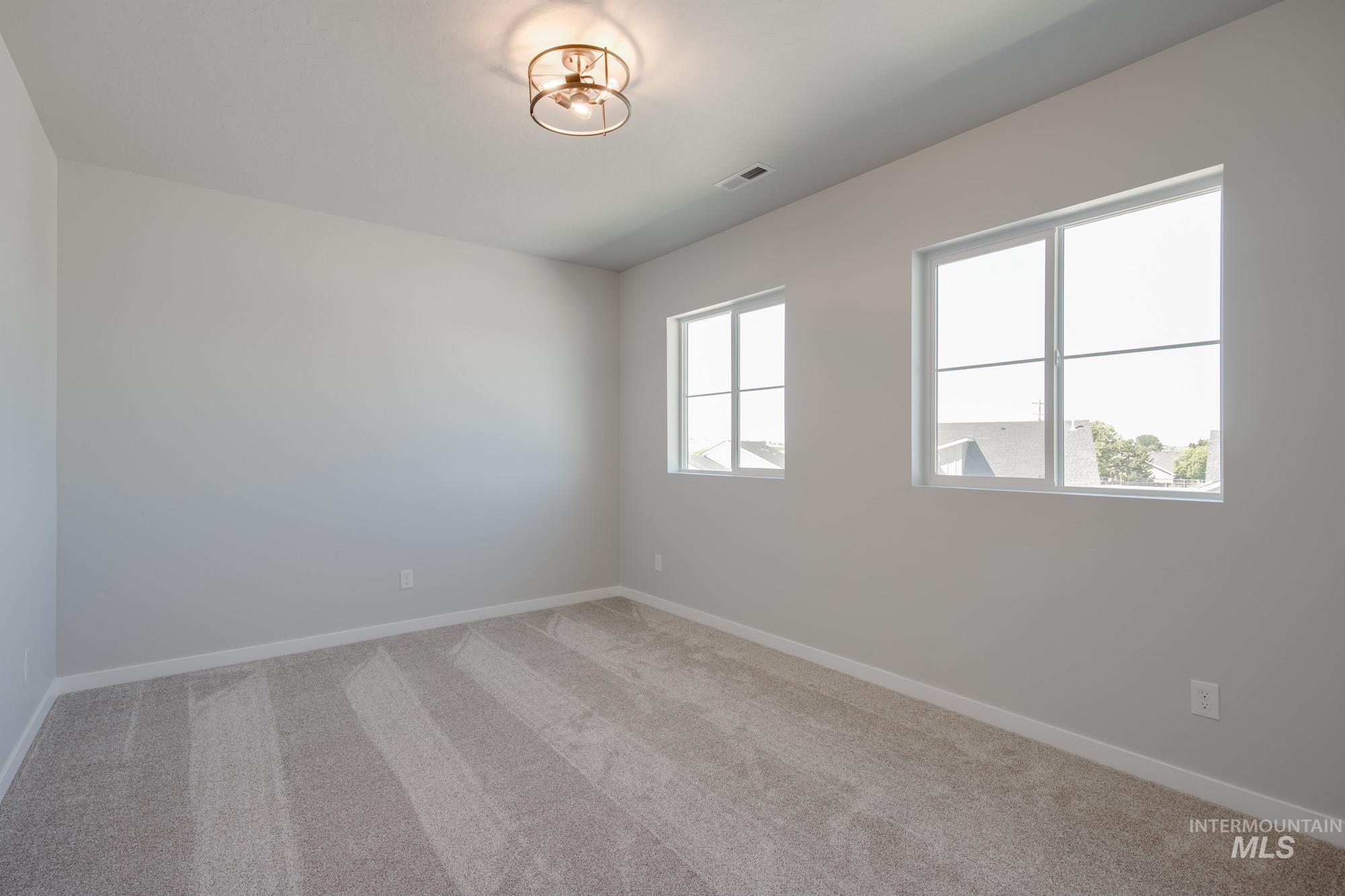 Unfurnished room featuring light carpet and baseboards