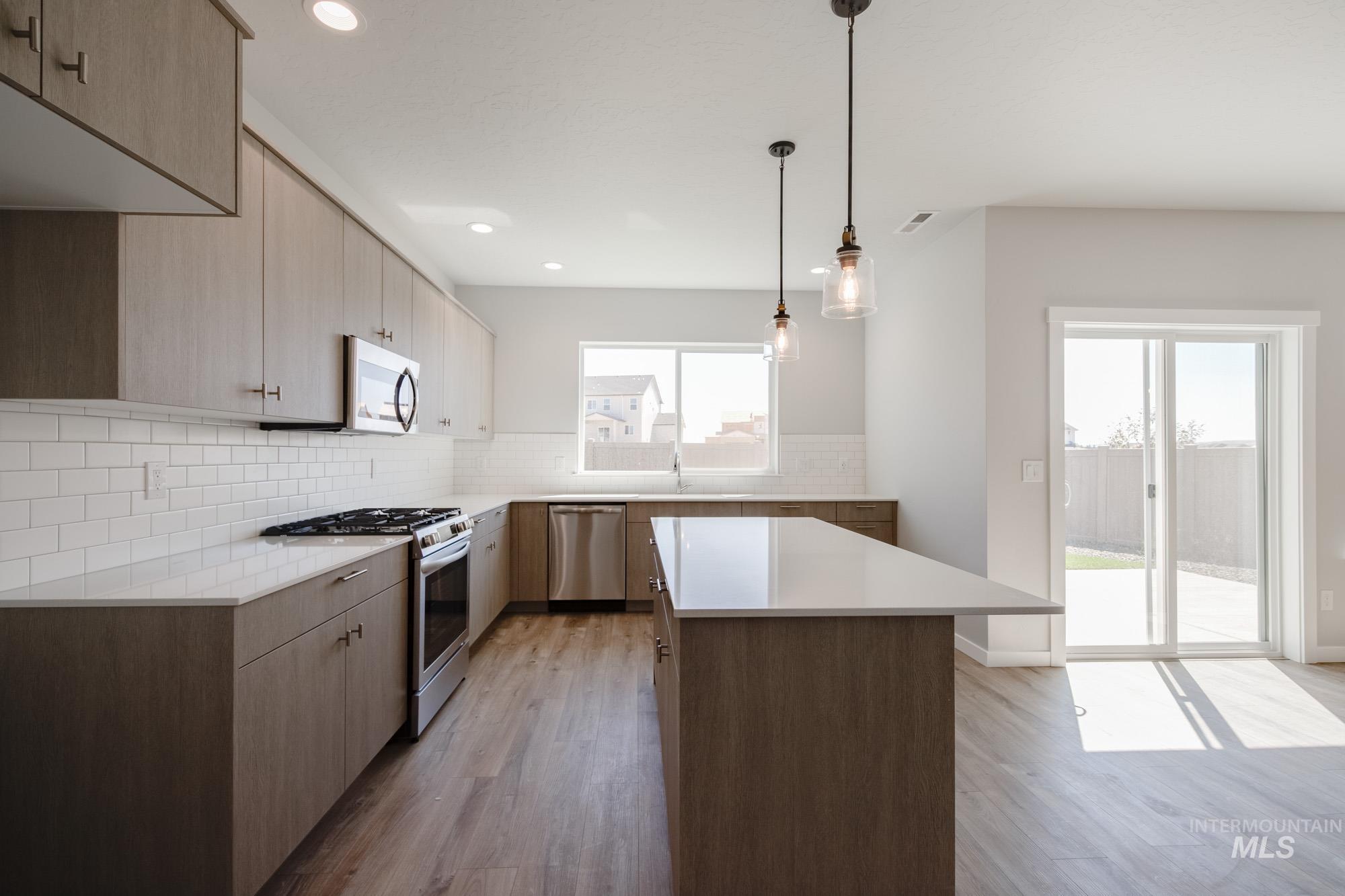 Kitchen with appliances with stainless steel finishes, tasteful backsplash, dark wood-type flooring, light stone counters, and recessed lighting
