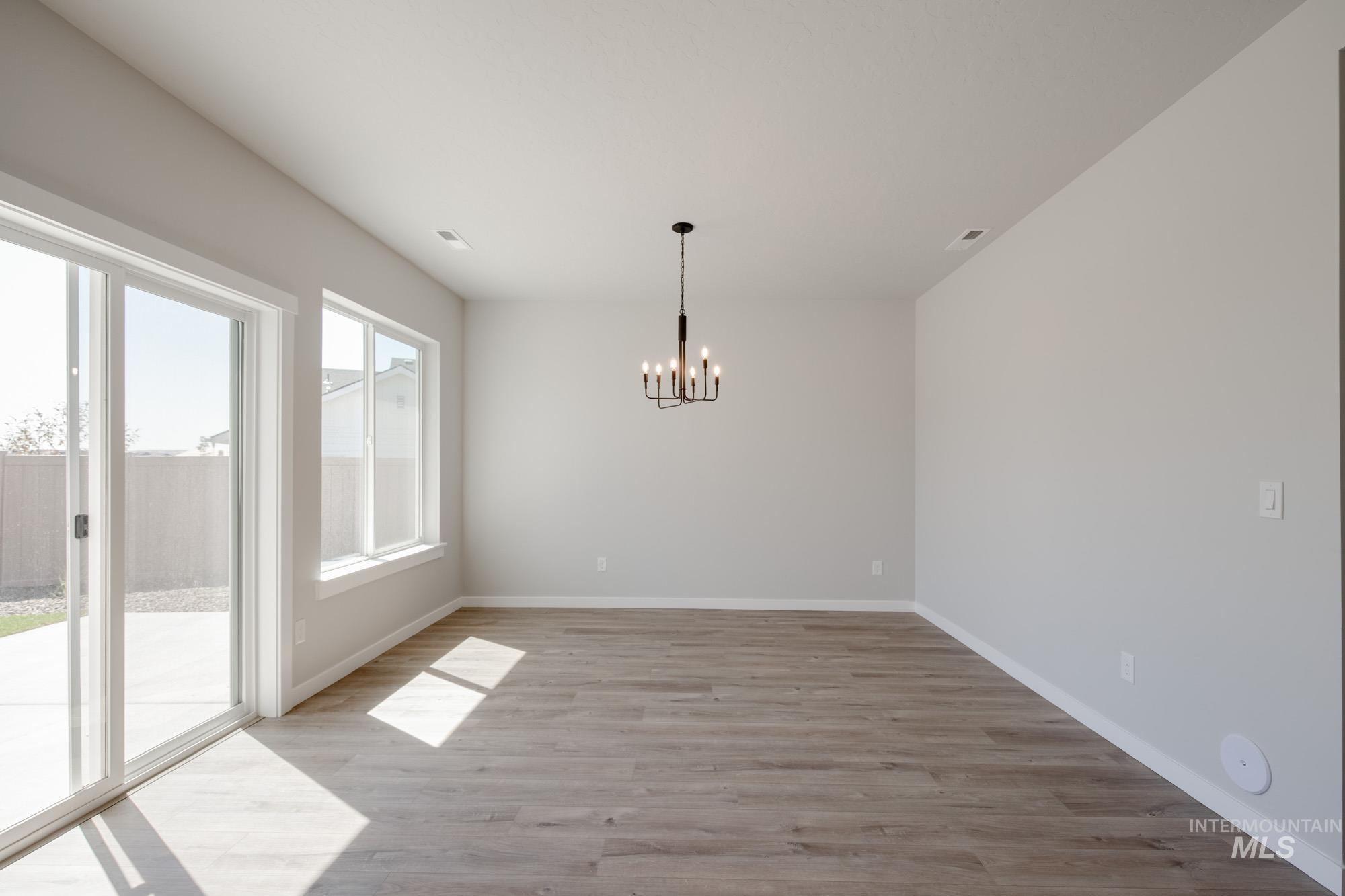 Unfurnished dining area featuring light wood finished floors and a chandelier