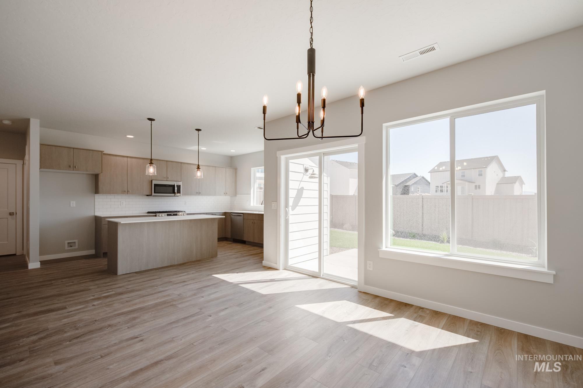 Kitchen with light countertops, open floor plan, a kitchen island, hanging light fixtures, and tasteful backsplash