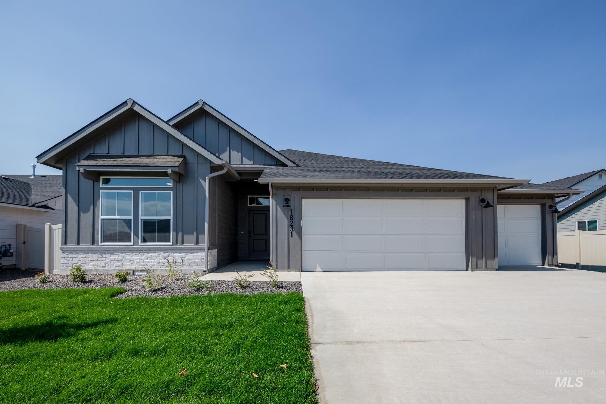 Ranch-style house featuring board and batten siding, stone siding, driveway, a garage, and a front lawn