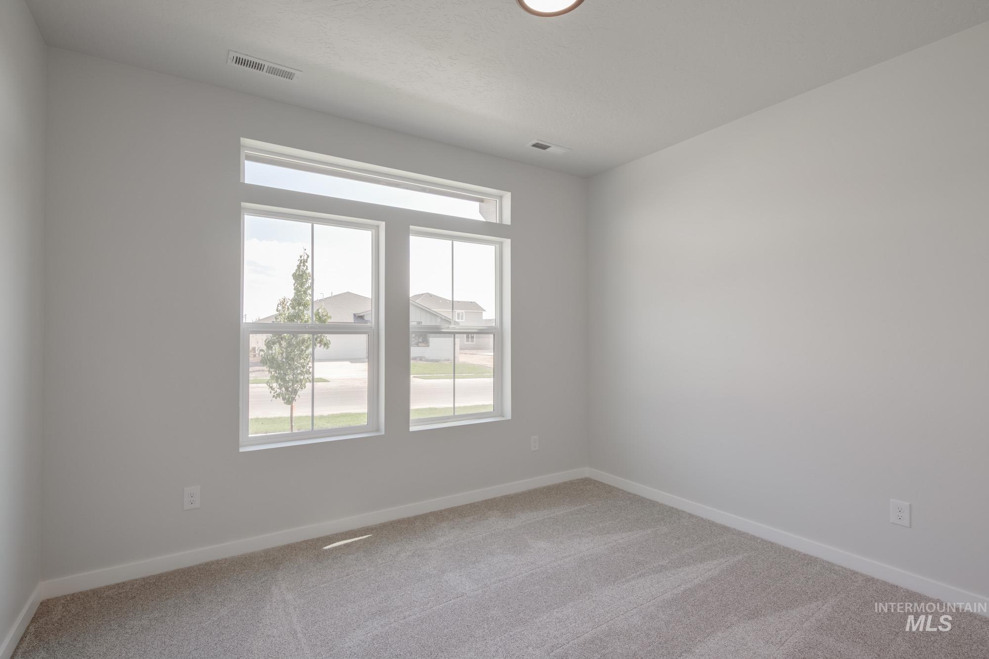 Spare room featuring light colored carpet and baseboards