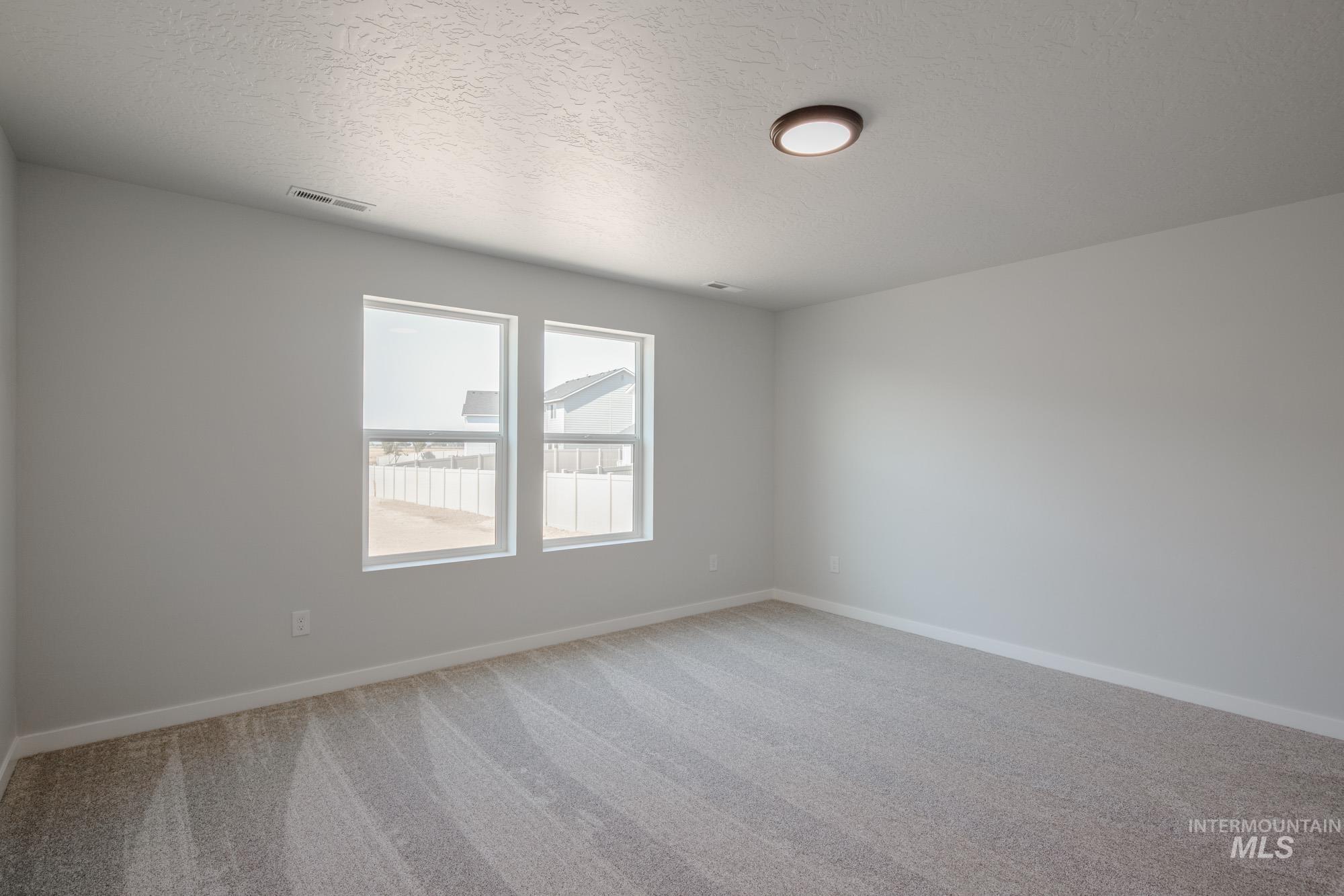 Spare room with light colored carpet and a textured ceiling