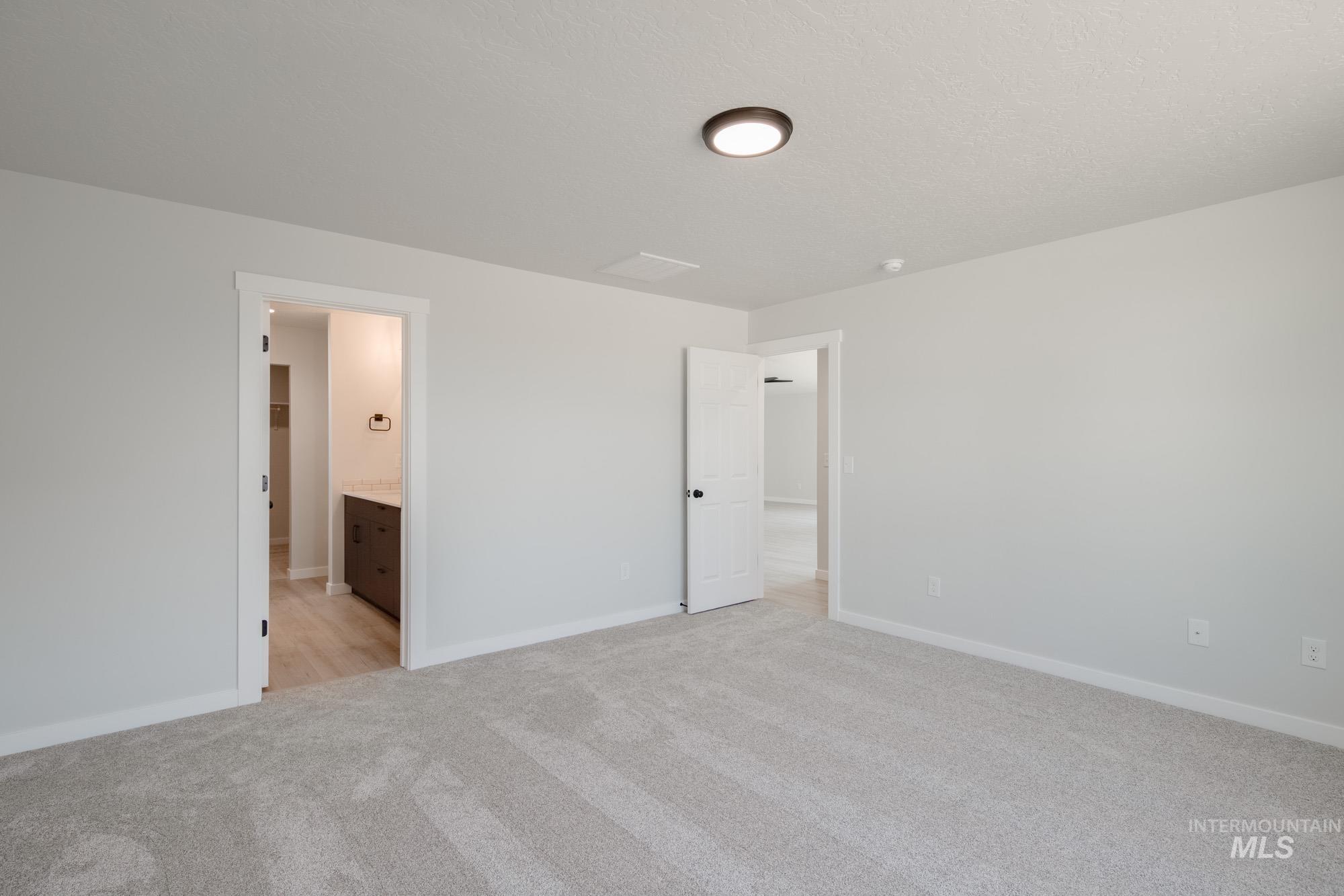 Unfurnished bedroom with light carpet and ensuite bath