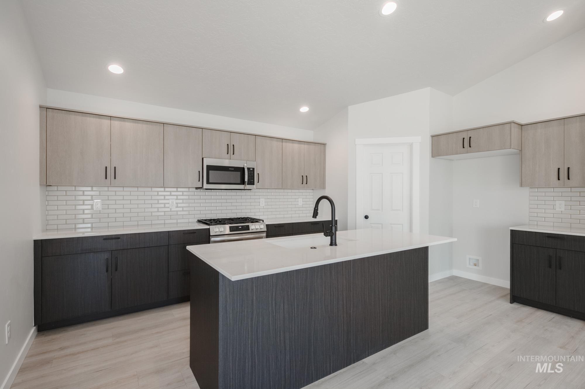 Kitchen featuring tasteful backsplash, light brown cabinets, stainless steel appliances, light stone counters, and recessed lighting