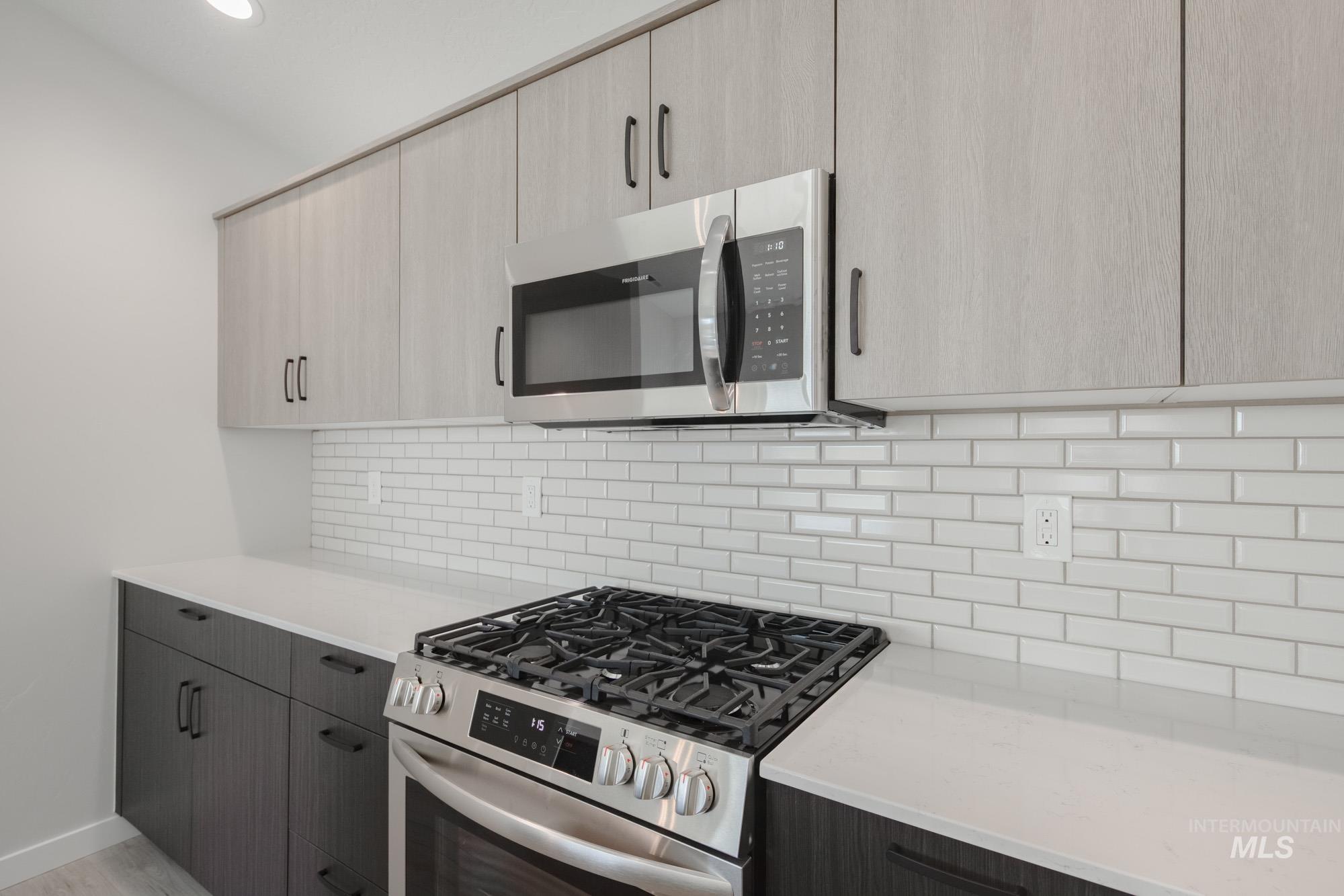 Kitchen featuring appliances with stainless steel finishes, decorative backsplash, light stone countertops, modern cabinets, and recessed lighting