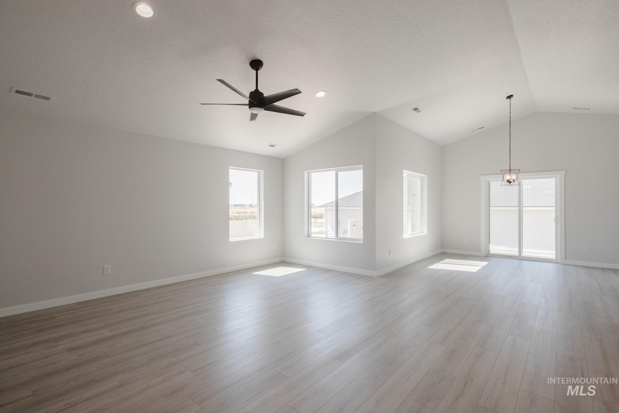 Unfurnished living room featuring vaulted ceiling, light wood-type flooring, a ceiling fan, and recessed lighting