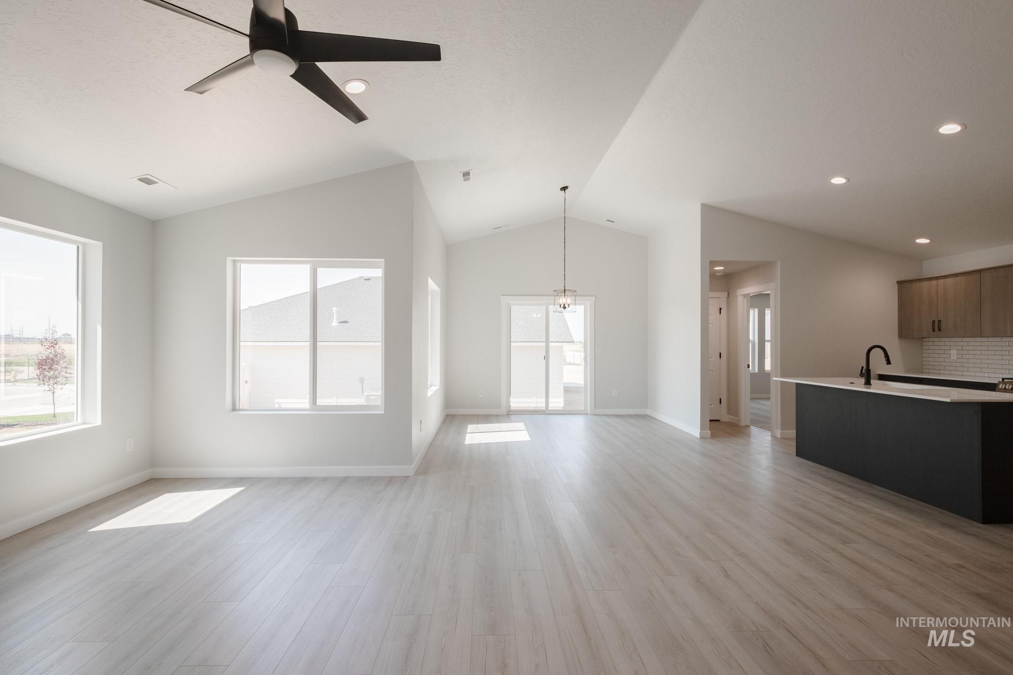 Unfurnished living room with light wood-style flooring, a ceiling fan, lofted ceiling, and recessed lighting