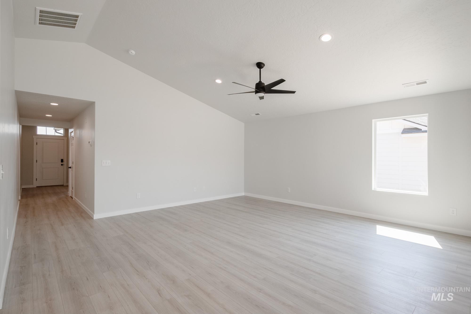 Unfurnished living room featuring lofted ceiling, light wood-style flooring, and recessed lighting