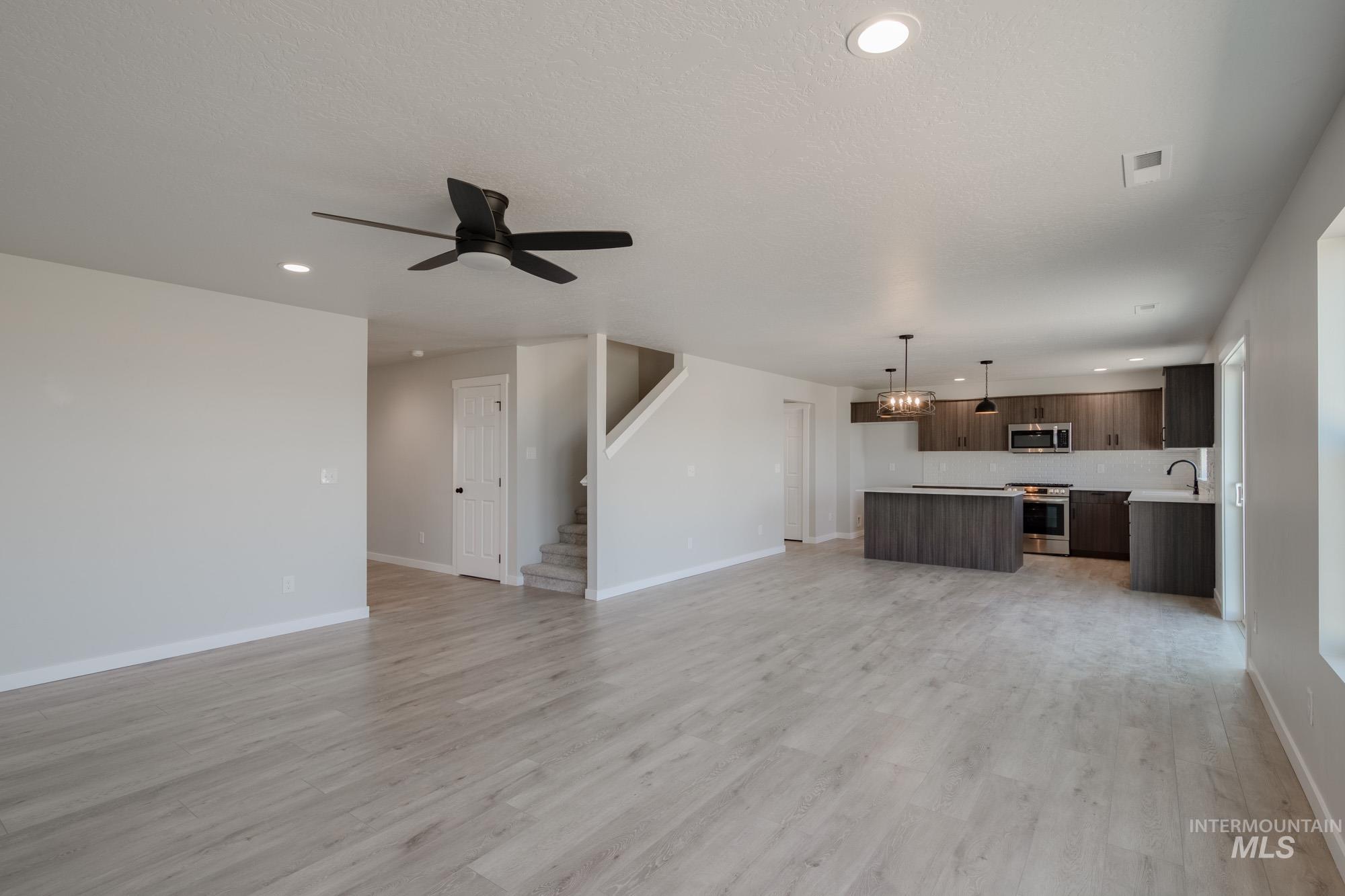 Unfurnished living room with recessed lighting, ceiling fan, light wood-type flooring, and stairway