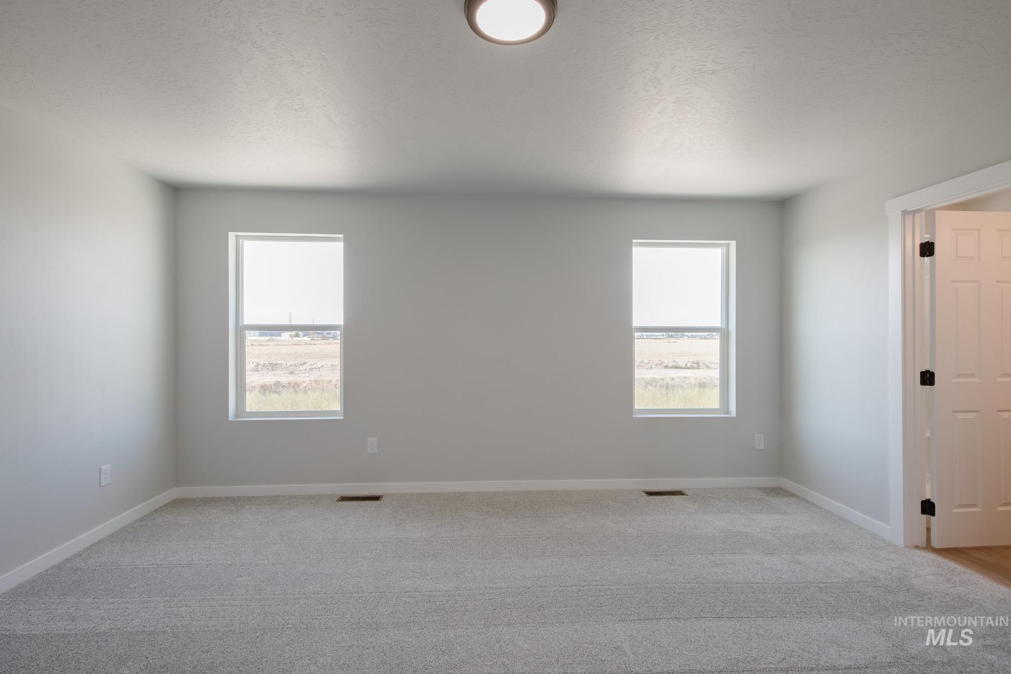 Empty room featuring a textured ceiling and light colored carpet