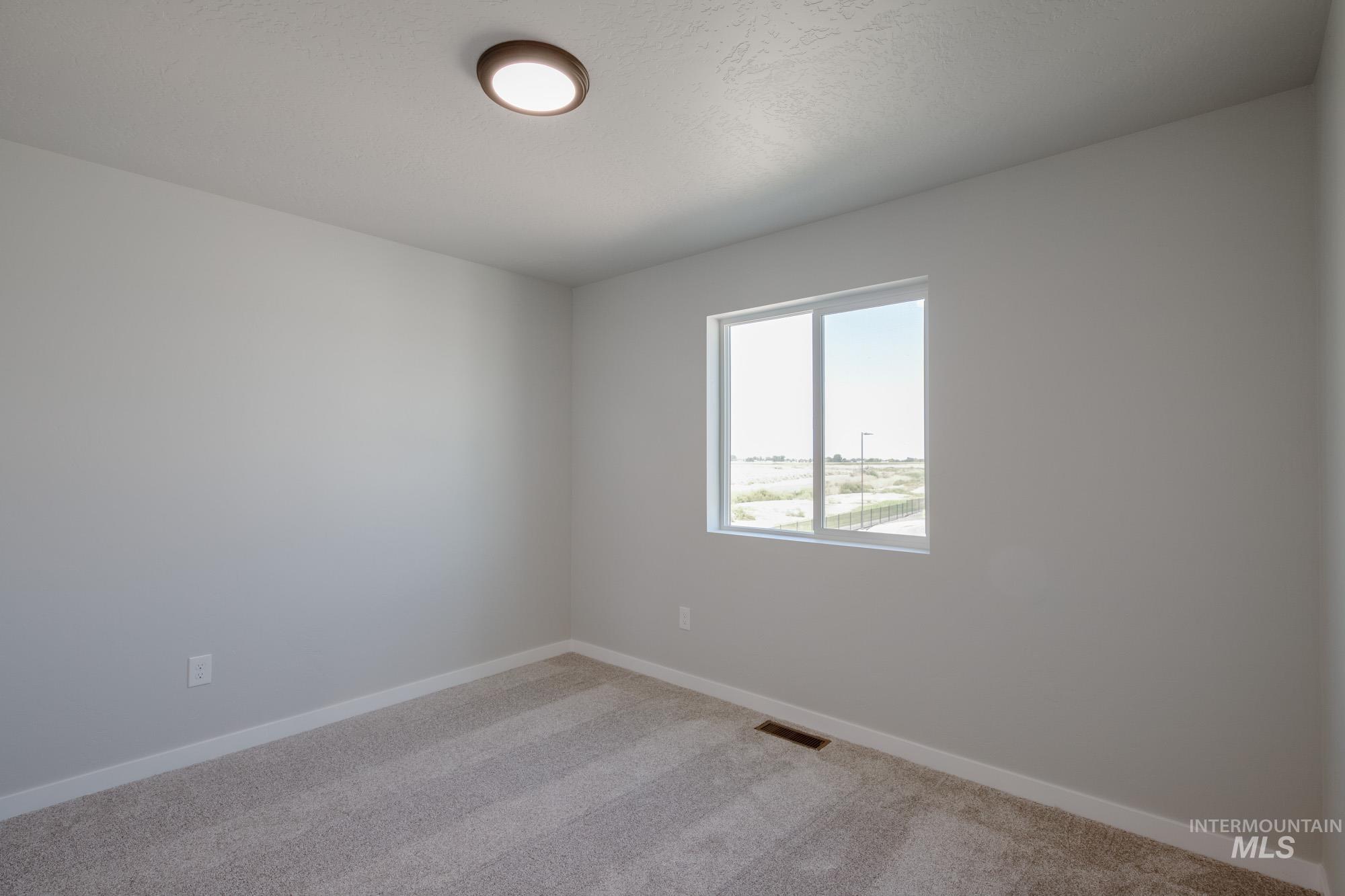 Spare room featuring light colored carpet and baseboards