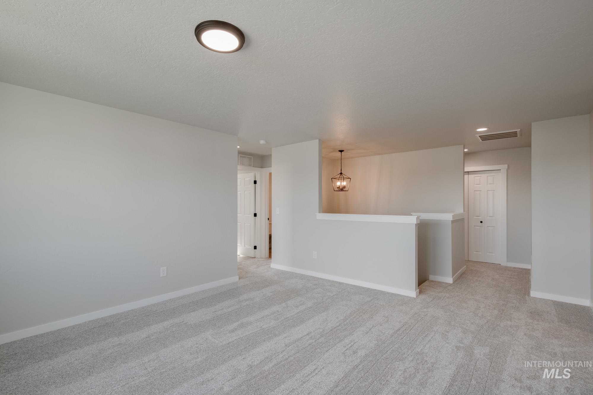 Empty room with light carpet and a chandelier