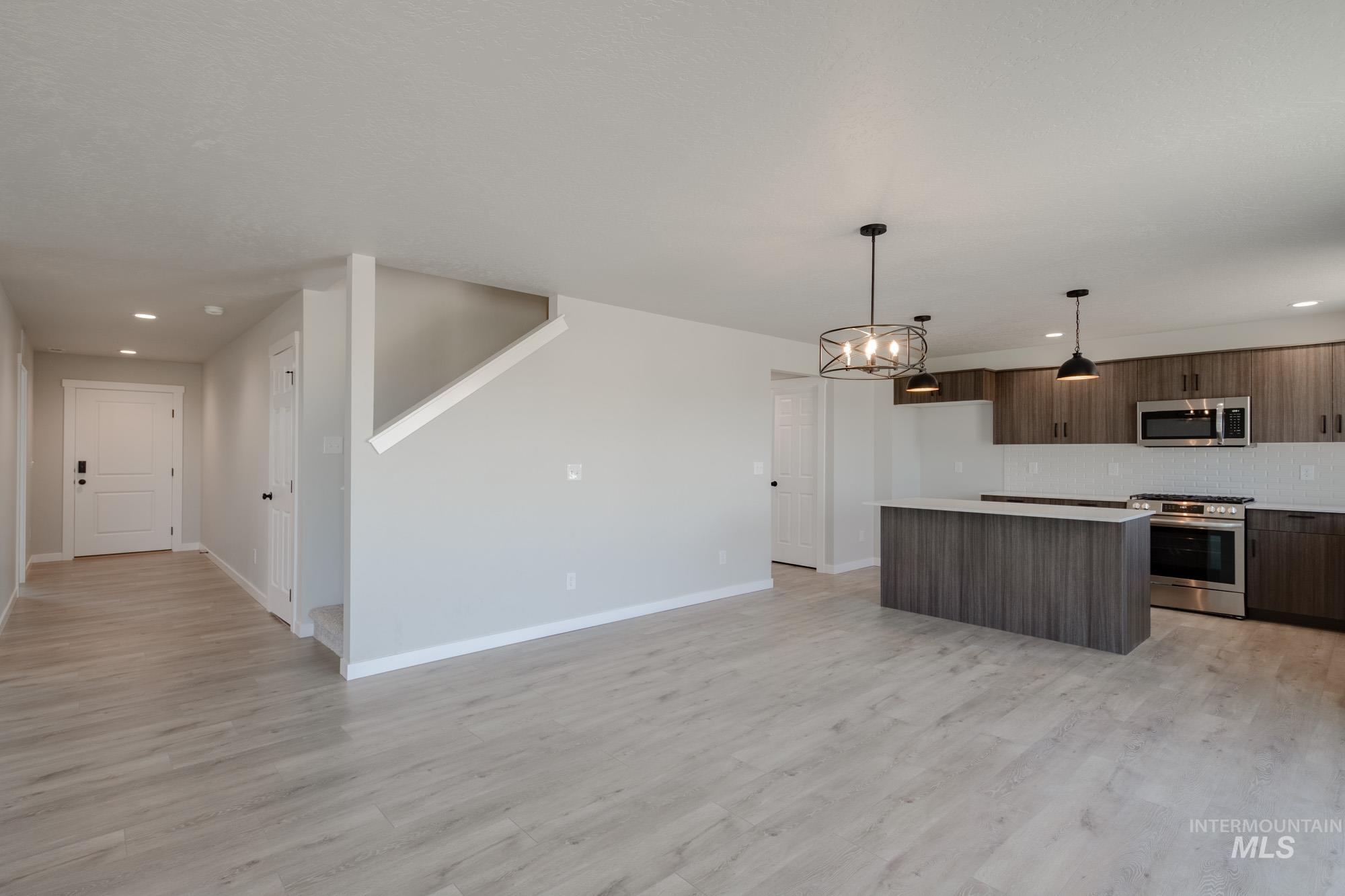 Kitchen with recessed lighting, a center island, appliances with stainless steel finishes, light countertops, and pendant lighting