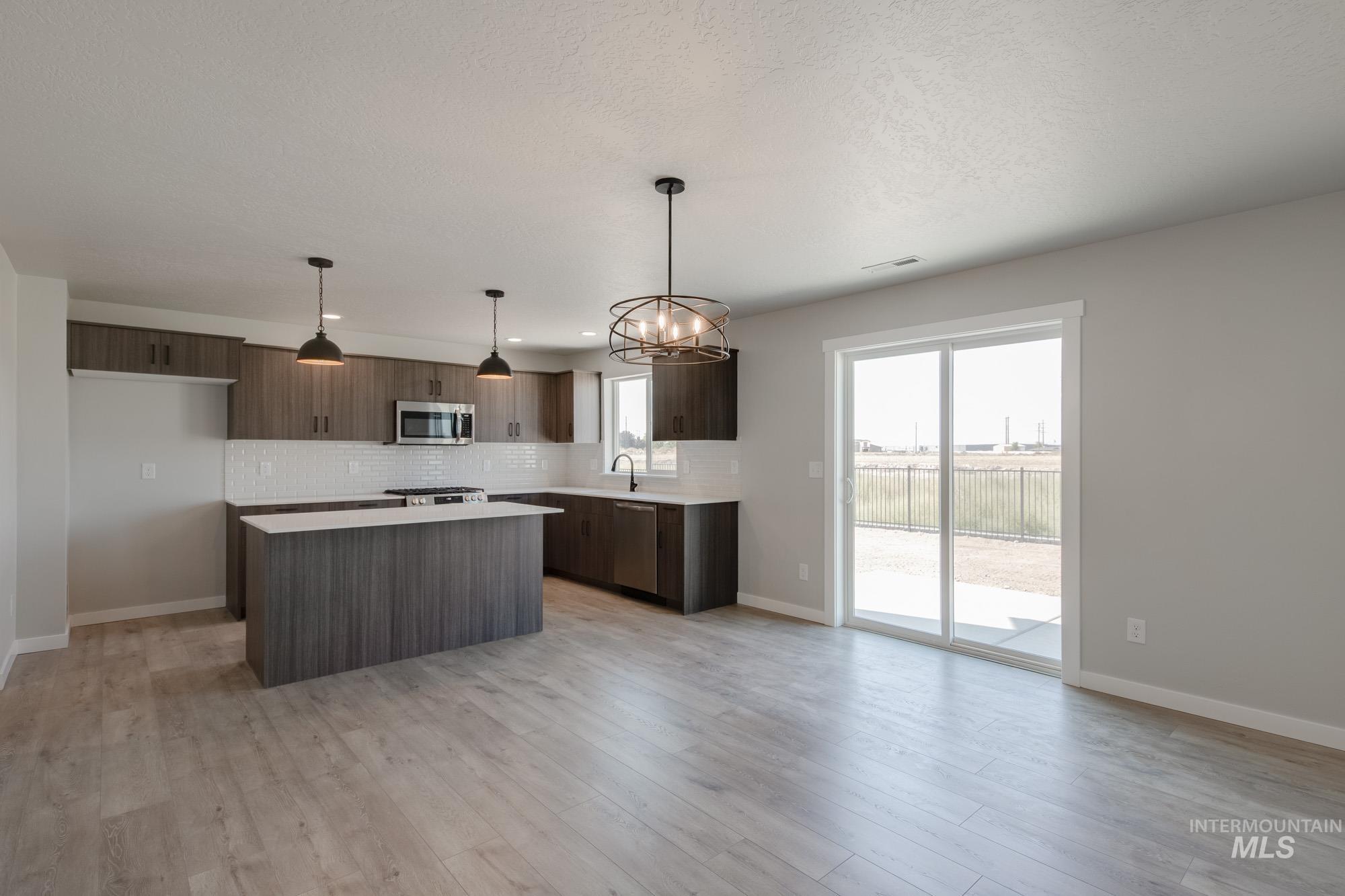 Kitchen featuring backsplash, light countertops, a kitchen island, modern cabinets, and a textured ceiling