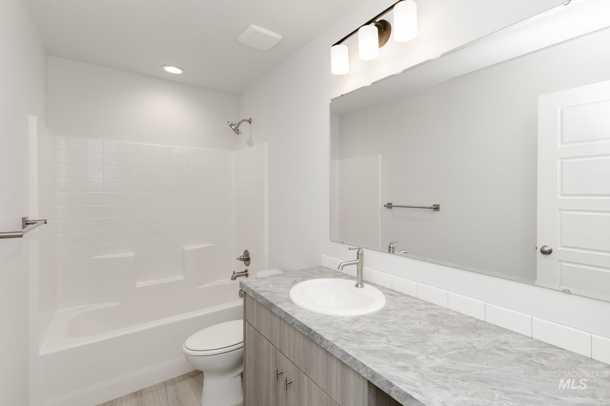 Bathroom with vanity, shower / tub combination, wood finished floors, and recessed lighting