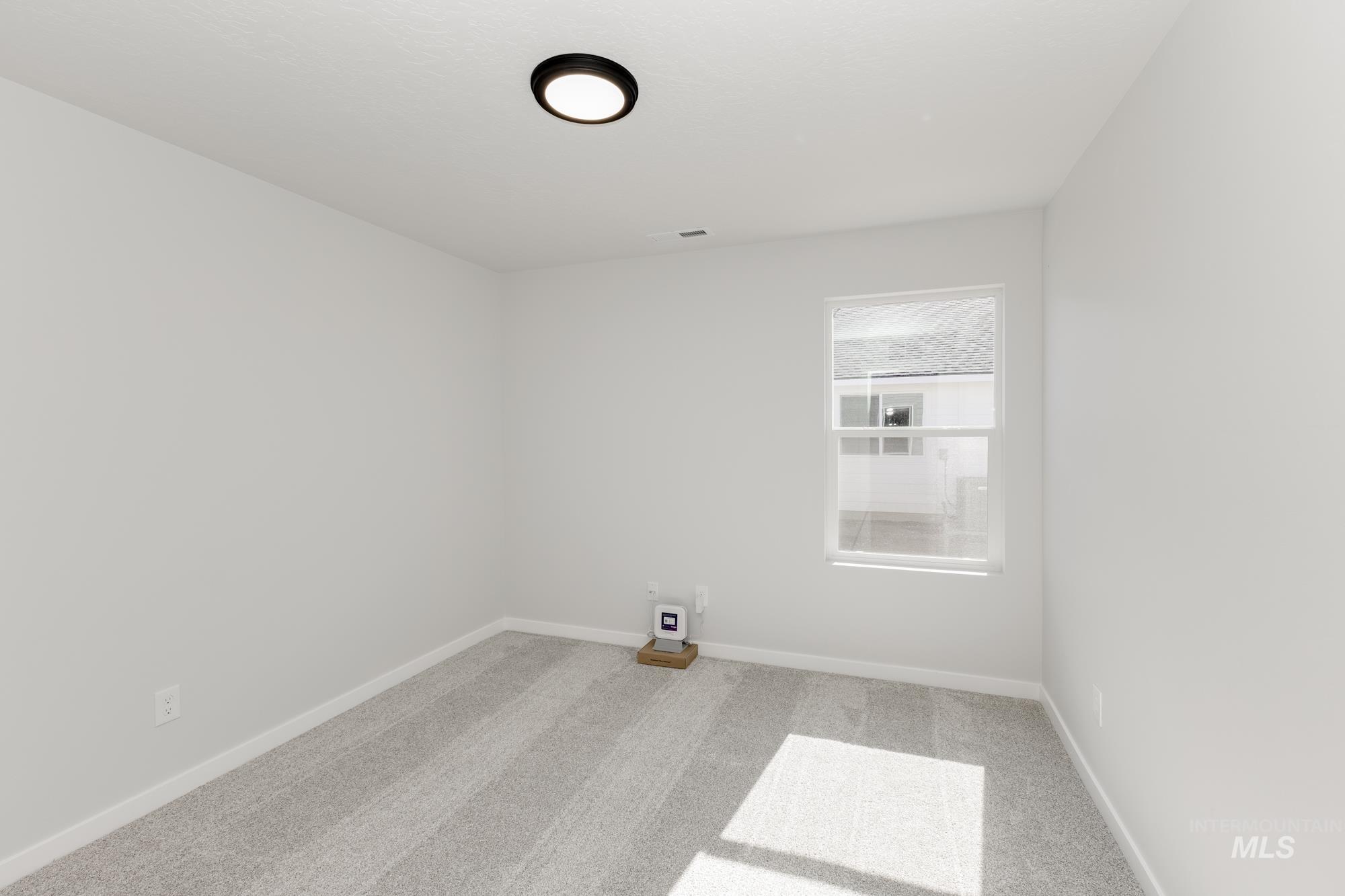 Spare room featuring light carpet and baseboards