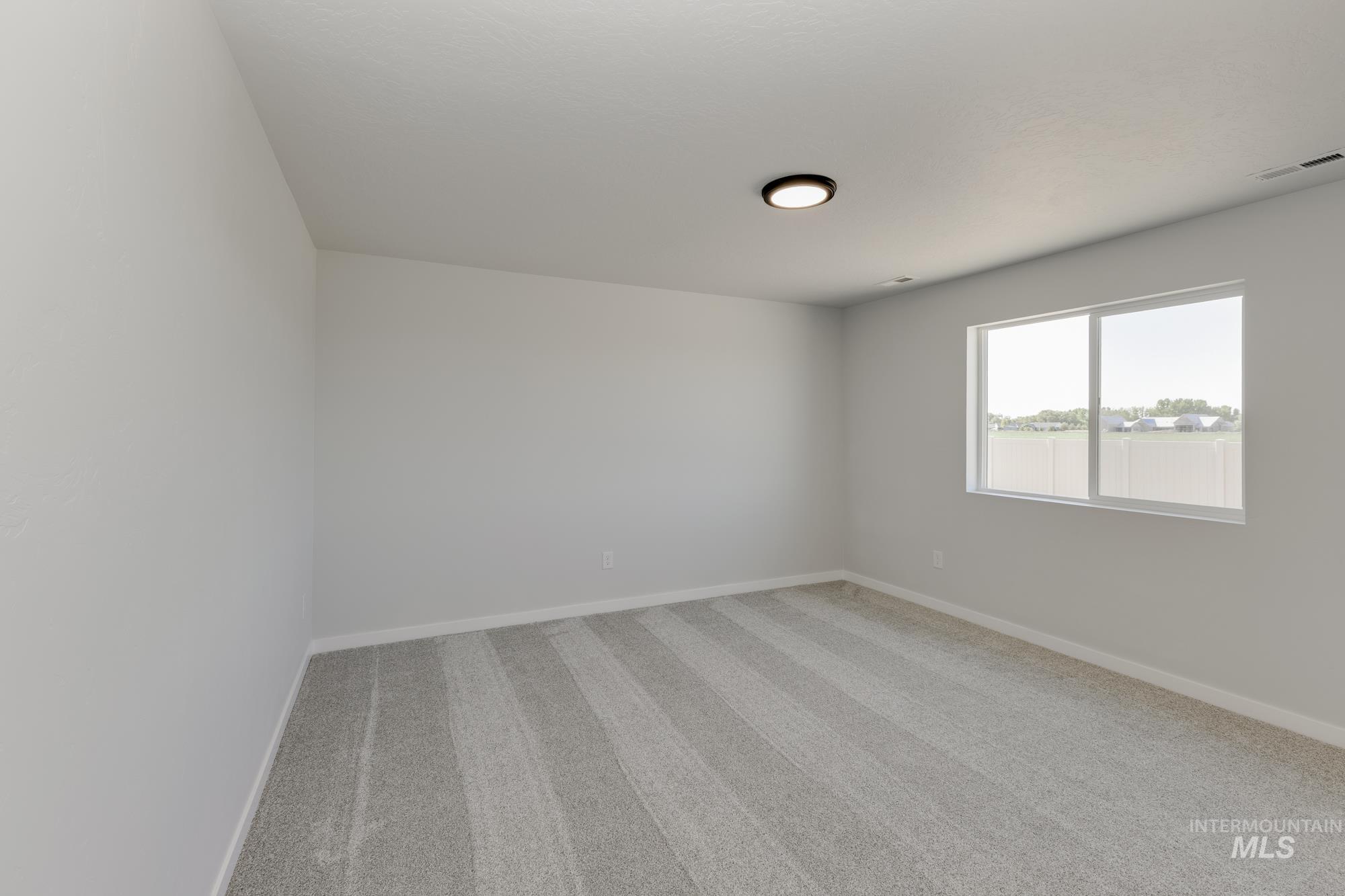 Spare room featuring light colored carpet and baseboards