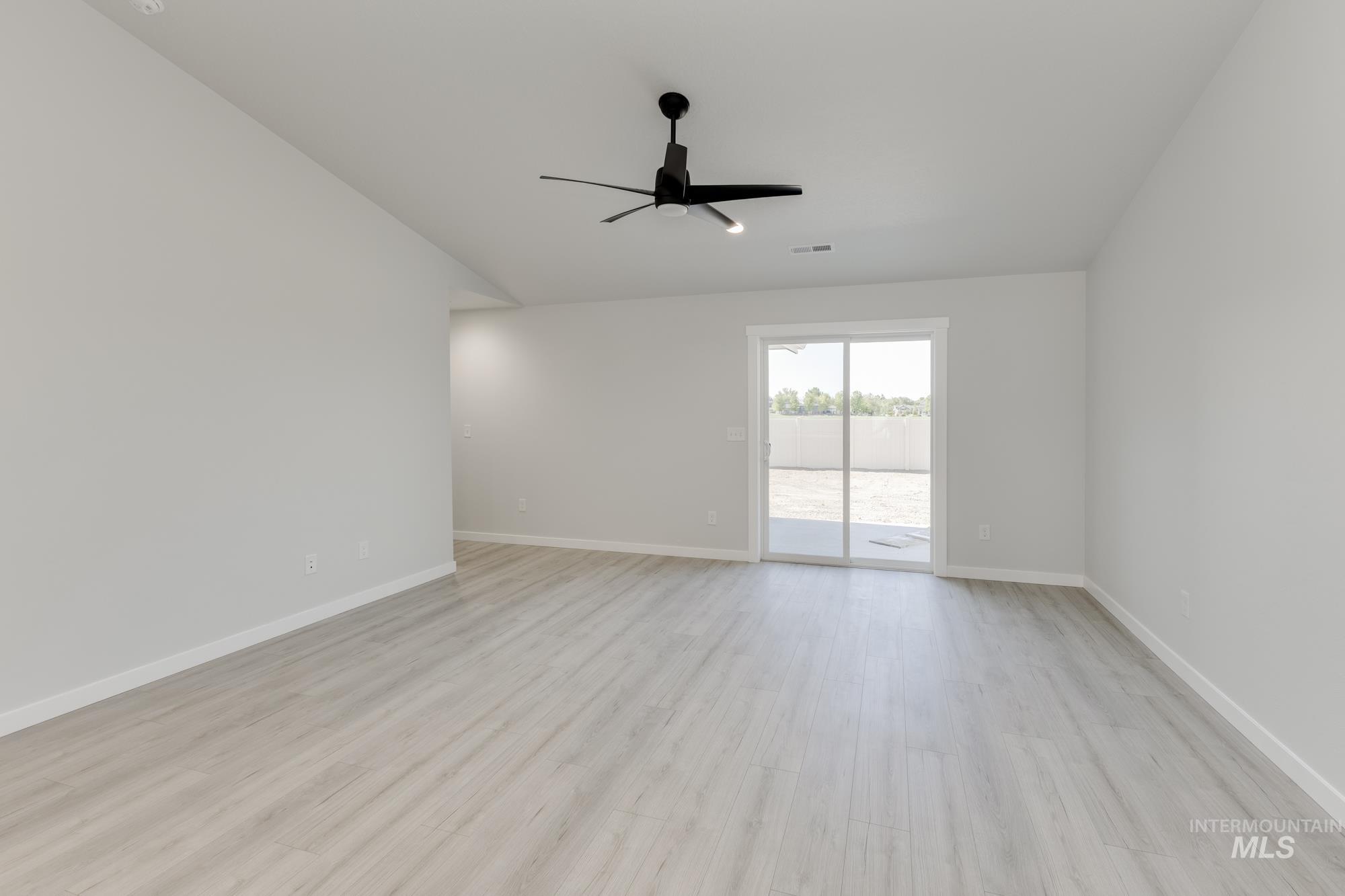 Empty room with vaulted ceiling, light wood-type flooring, and ceiling fan