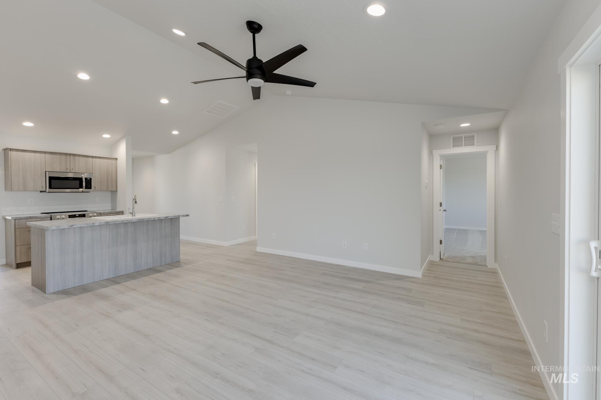 Kitchen featuring modern cabinets, lofted ceiling, recessed lighting, light brown cabinets, and light wood-style floors