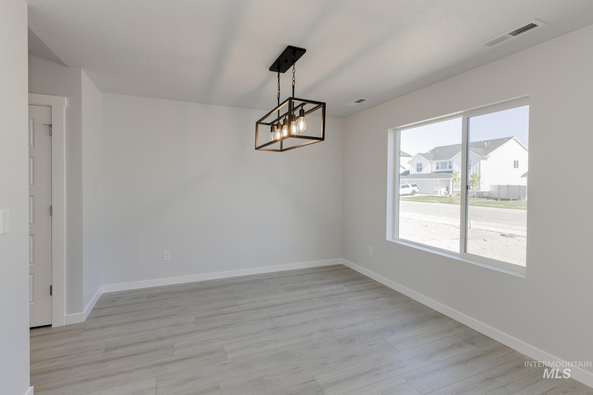 Unfurnished dining area featuring light wood finished floors and a chandelier