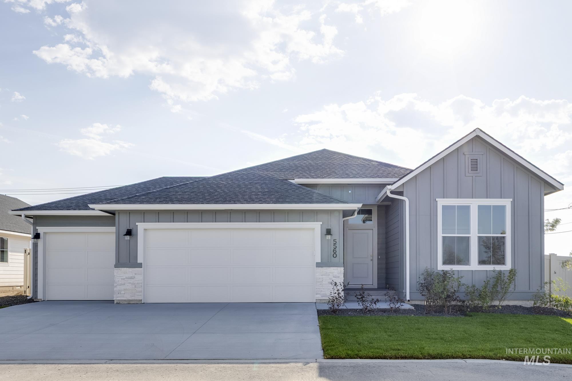 Single story home with board and batten siding, roof with shingles, a garage, concrete driveway, and stone siding