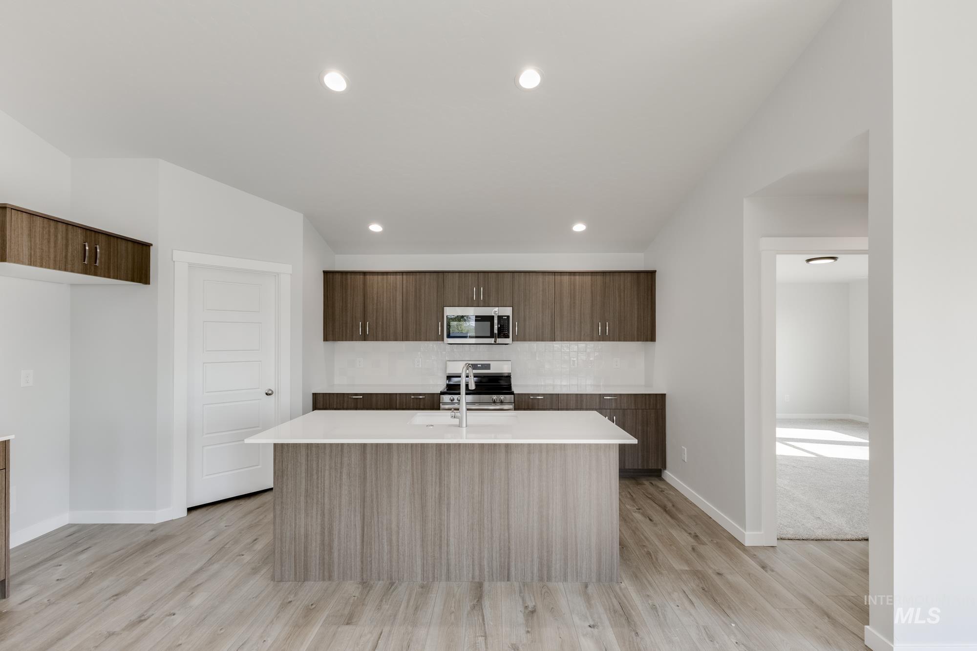Kitchen with a kitchen island with sink, modern cabinets, appliances with stainless steel finishes, light wood-style floors, and recessed lighting
