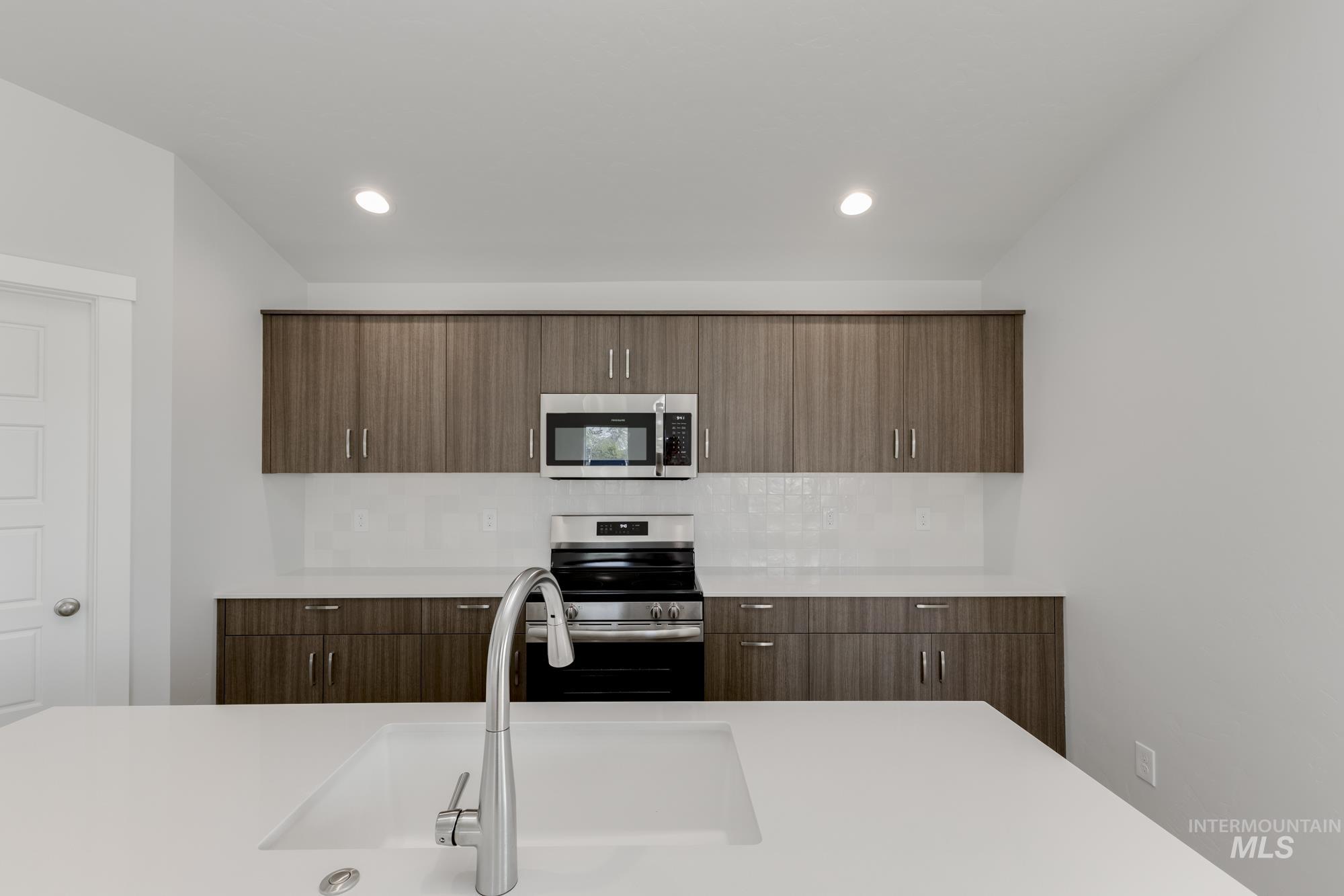 Kitchen featuring appliances with stainless steel finishes, modern cabinets, backsplash, recessed lighting, and light stone counters