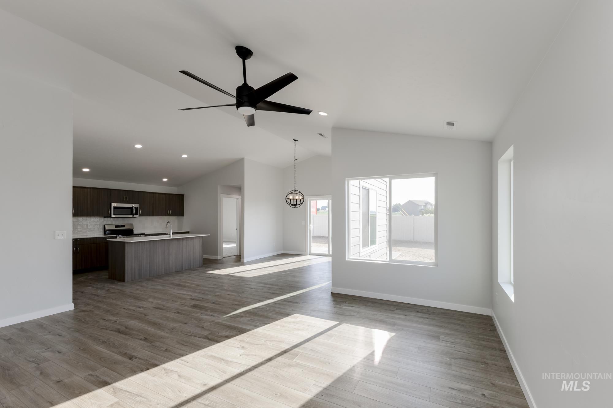 Unfurnished living room with lofted ceiling, light wood-style floors, ceiling fan, recessed lighting, and a chandelier