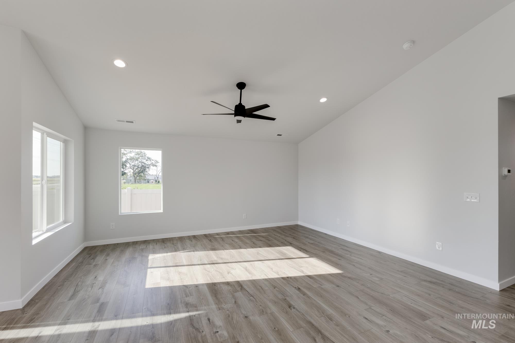 Empty room with recessed lighting, light wood-style flooring, ceiling fan, and lofted ceiling