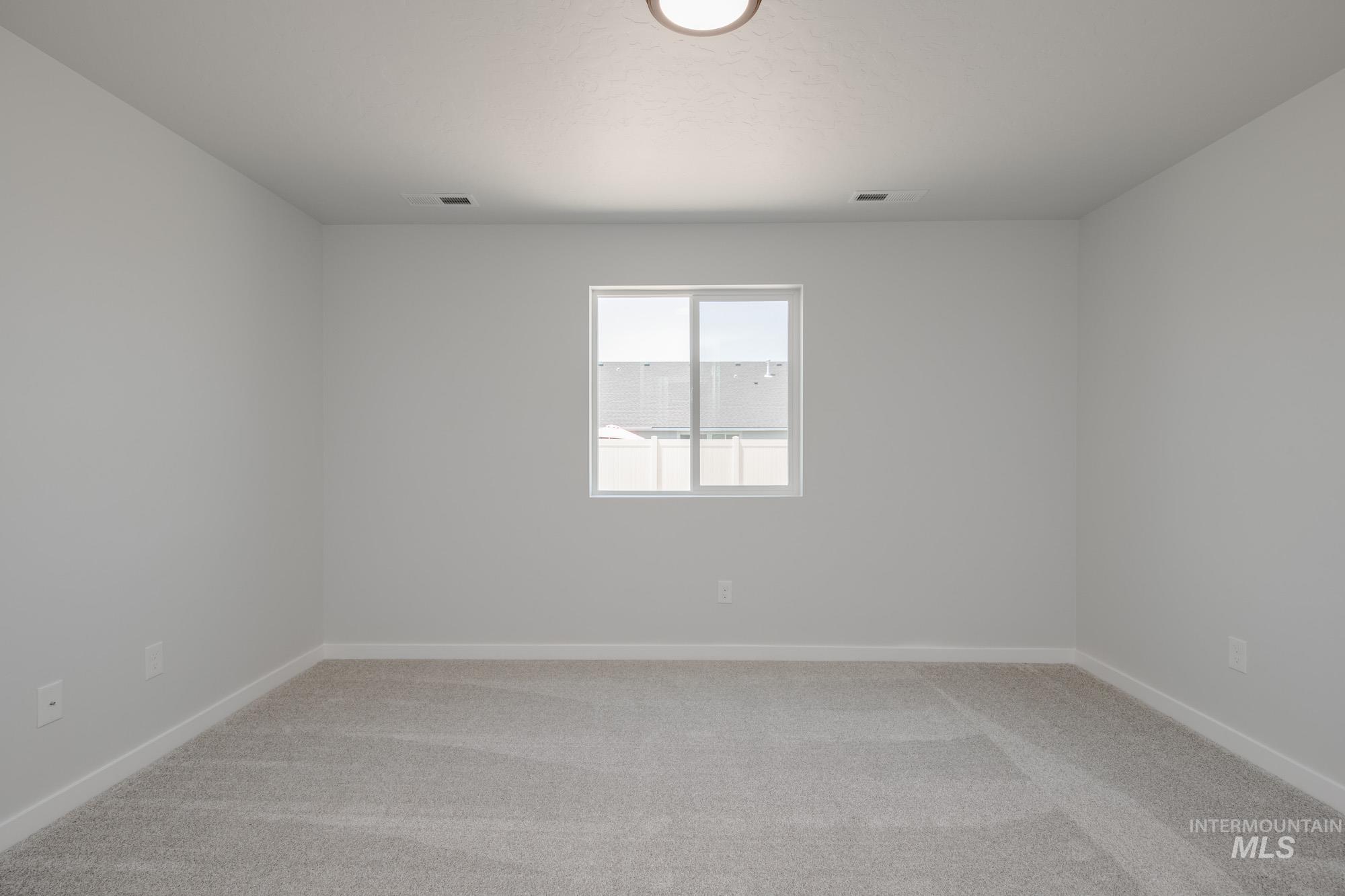 Empty room featuring light carpet and baseboards