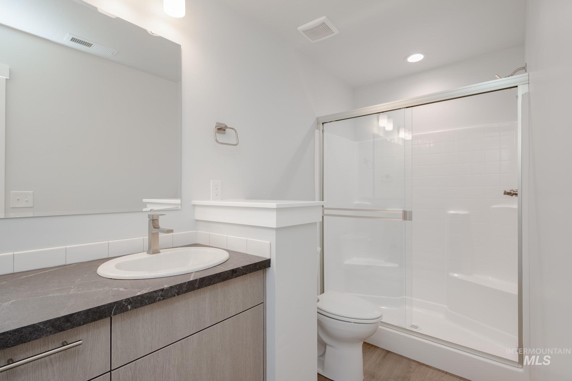 Bathroom with vanity, a shower stall, wood finished floors, and recessed lighting