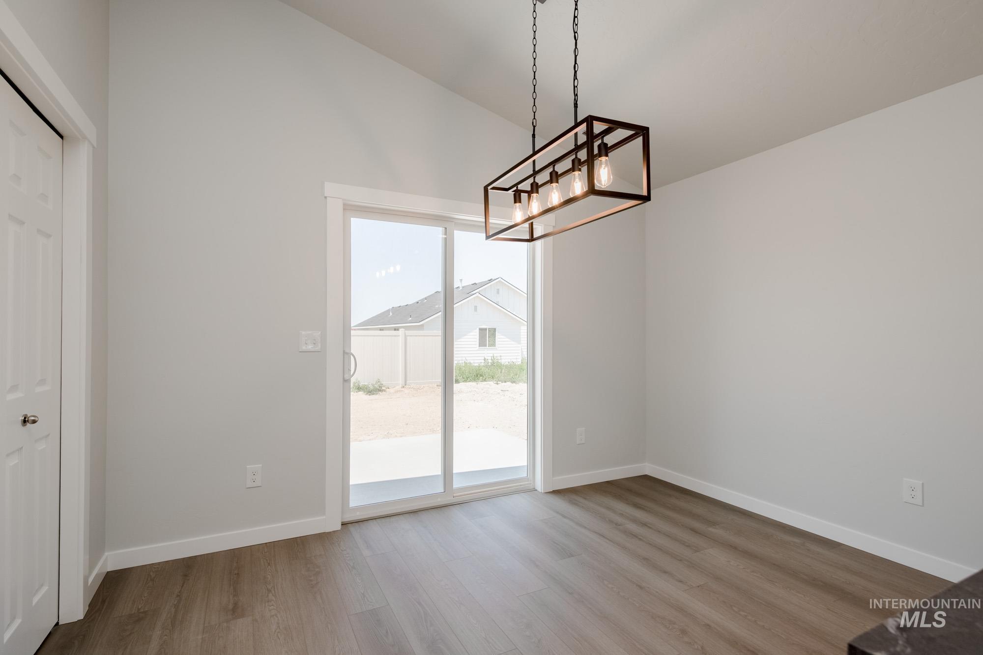 Unfurnished dining area featuring wood finished floors and lofted ceiling