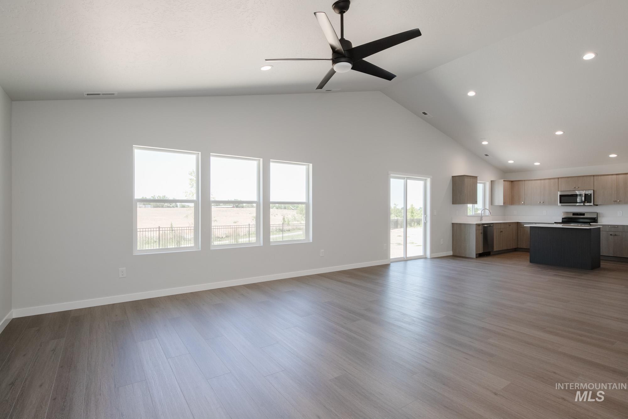 Unfurnished living room with recessed lighting, wood finished floors, ceiling fan, and high vaulted ceiling