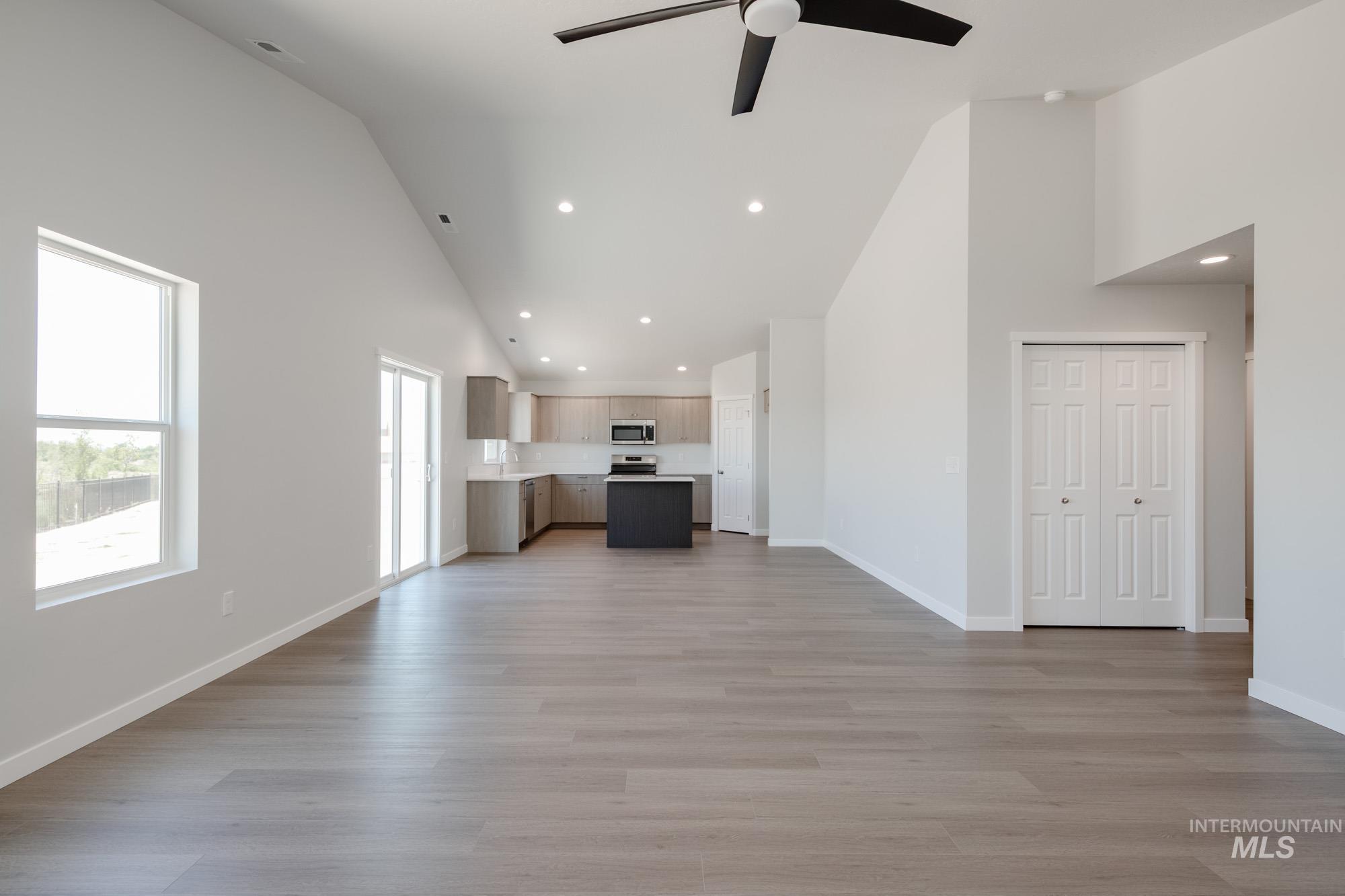 Unfurnished living room featuring high vaulted ceiling, ceiling fan, light wood-type flooring, and recessed lighting