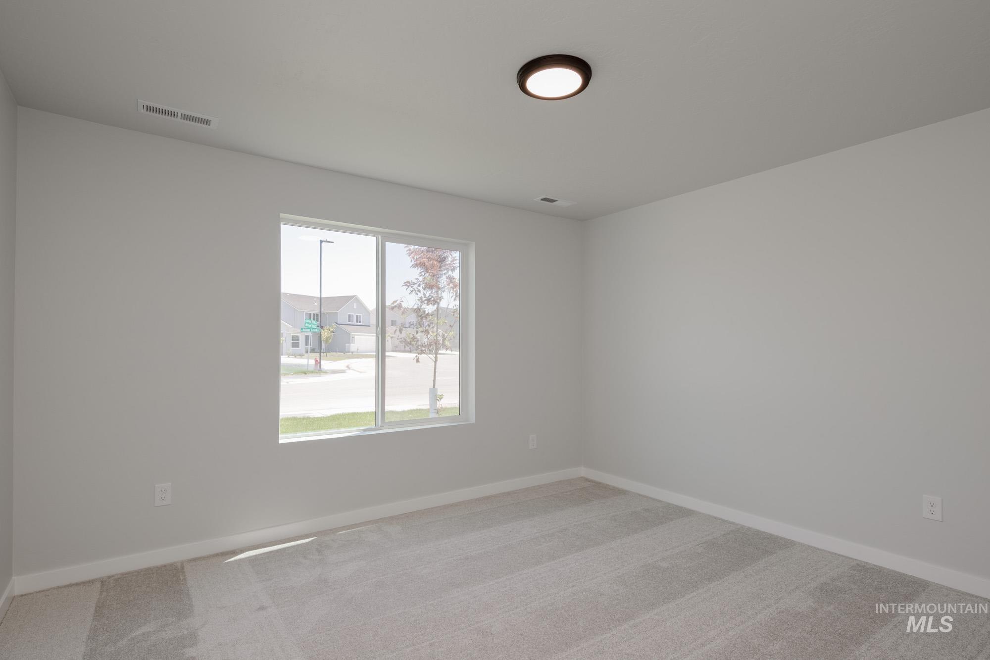 Carpeted spare room featuring baseboards