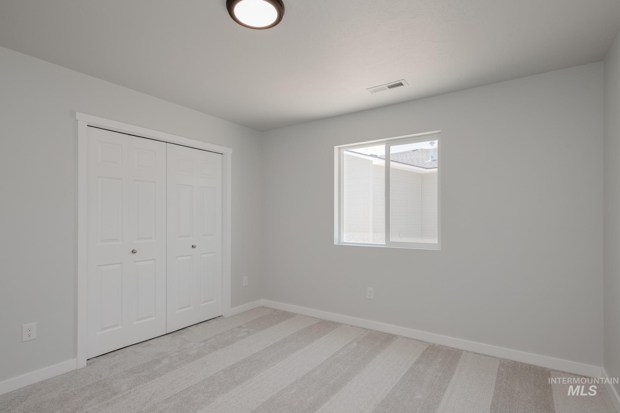 Unfurnished bedroom featuring light colored carpet and a closet