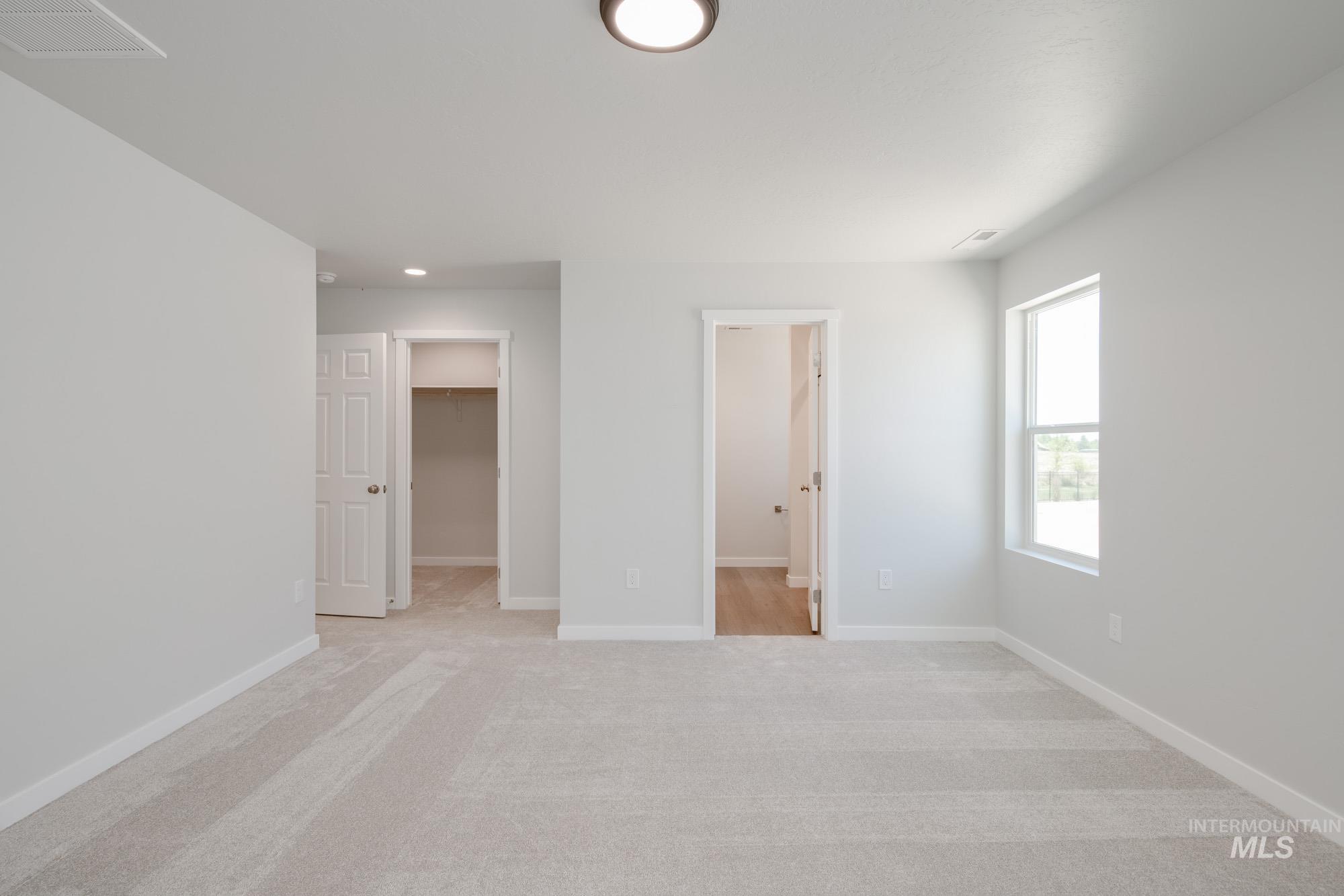 Unfurnished bedroom with a walk in closet, light colored carpet, and recessed lighting