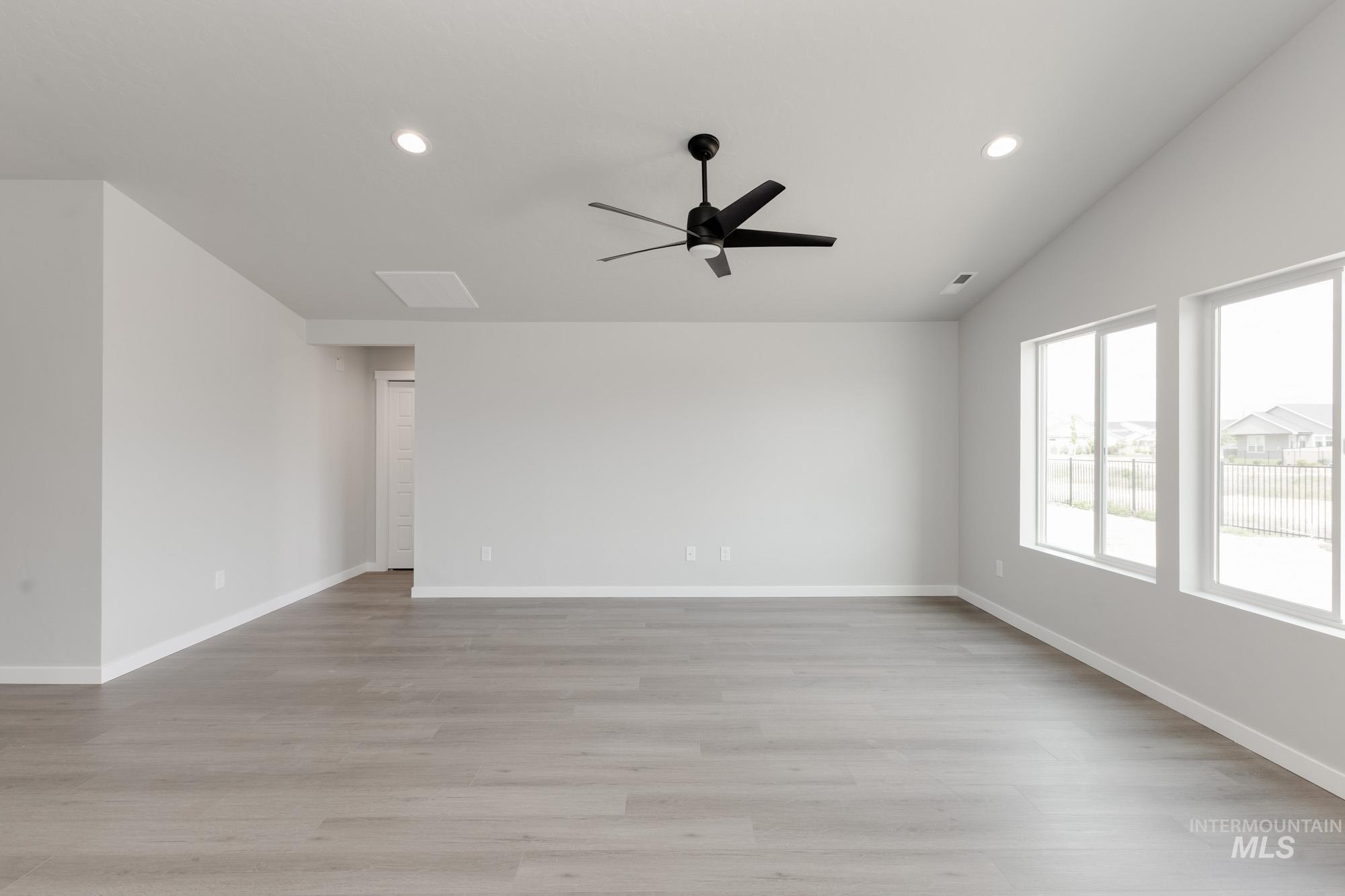 Spare room with vaulted ceiling, a ceiling fan, light wood-type flooring, and recessed lighting