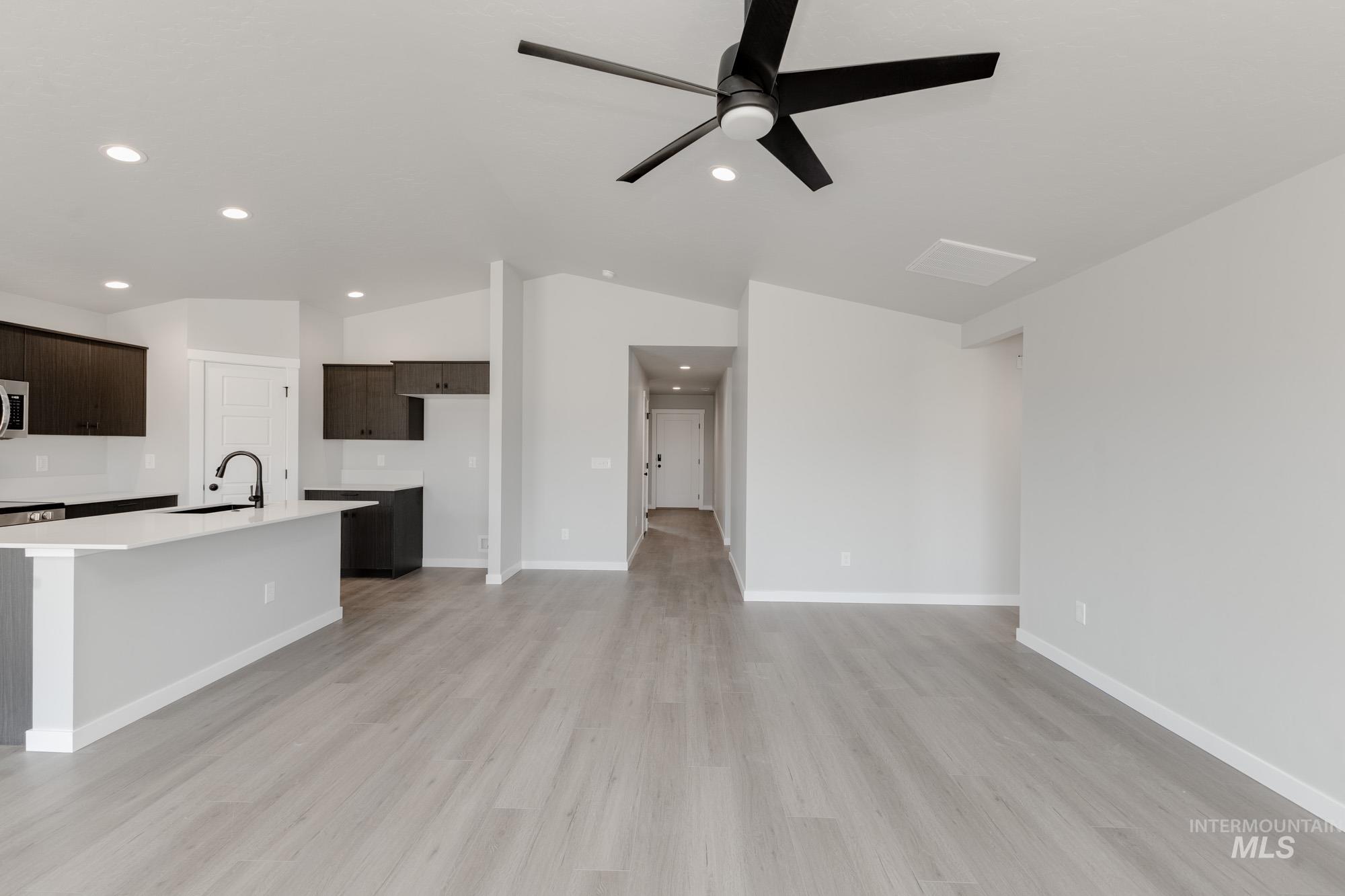 Unfurnished living room with vaulted ceiling, light wood finished floors, a ceiling fan, and recessed lighting