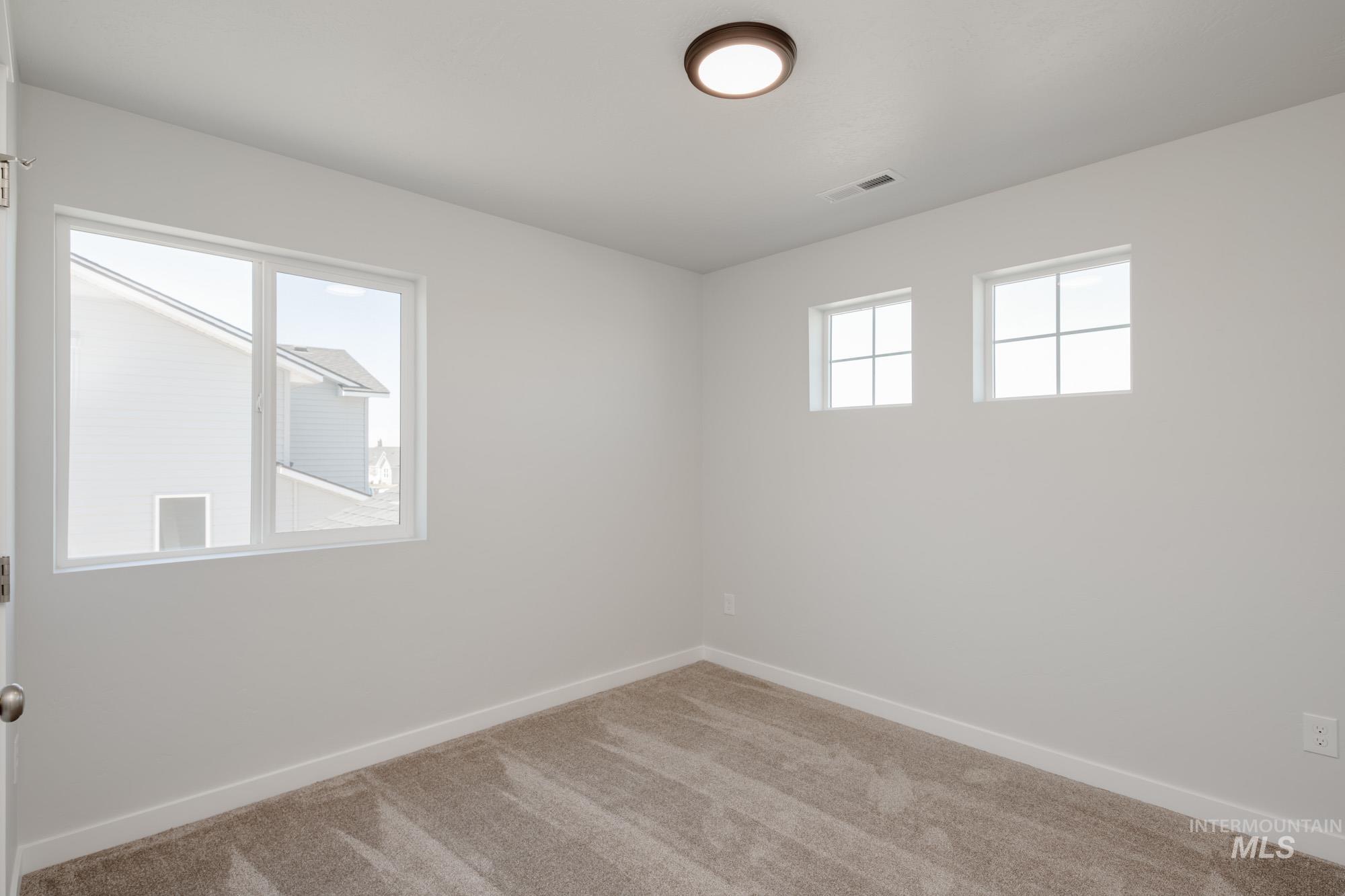 Carpeted spare room featuring baseboards