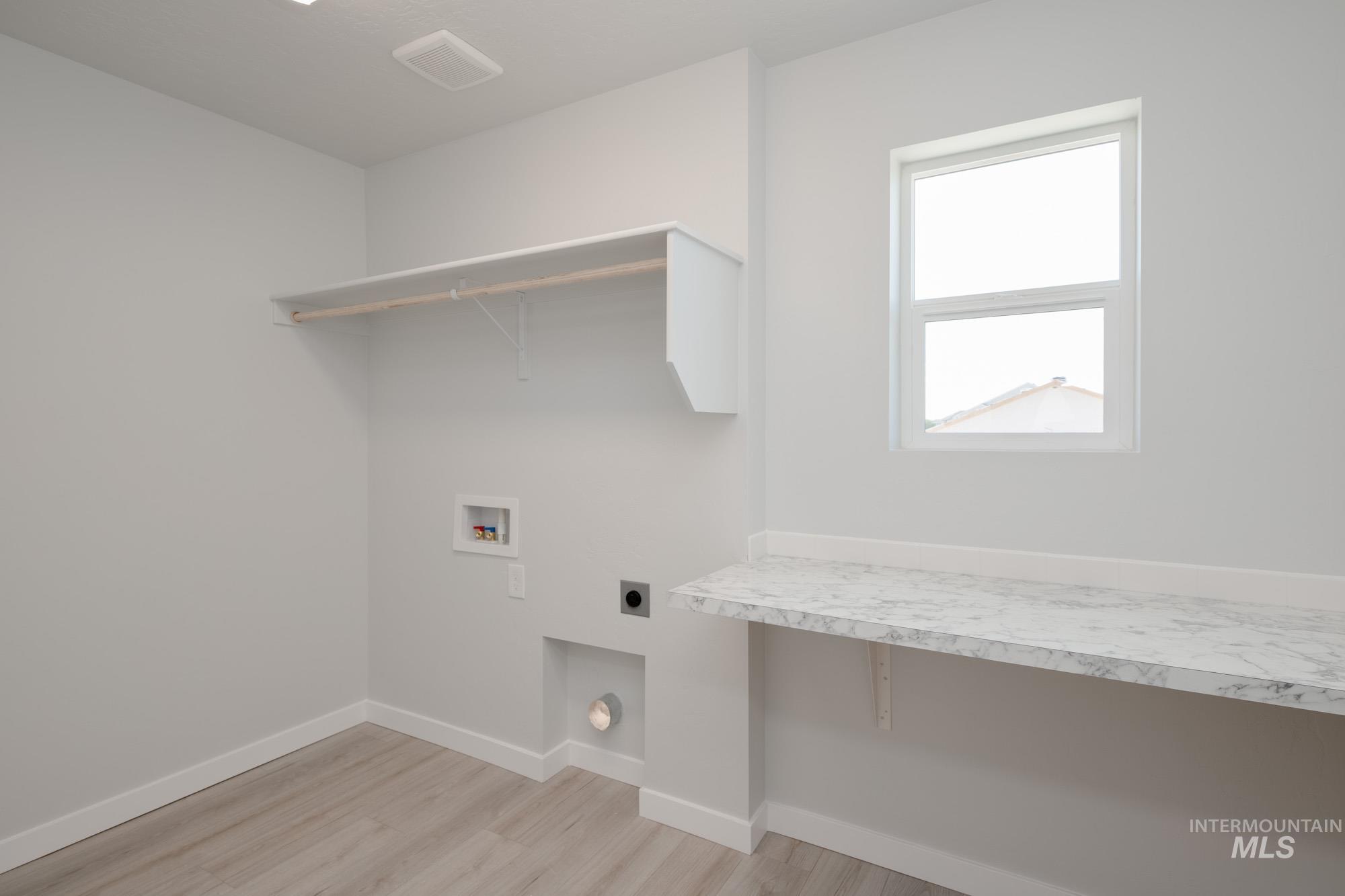 Washroom with hookup for an electric dryer, washer hookup, and light wood-type flooring