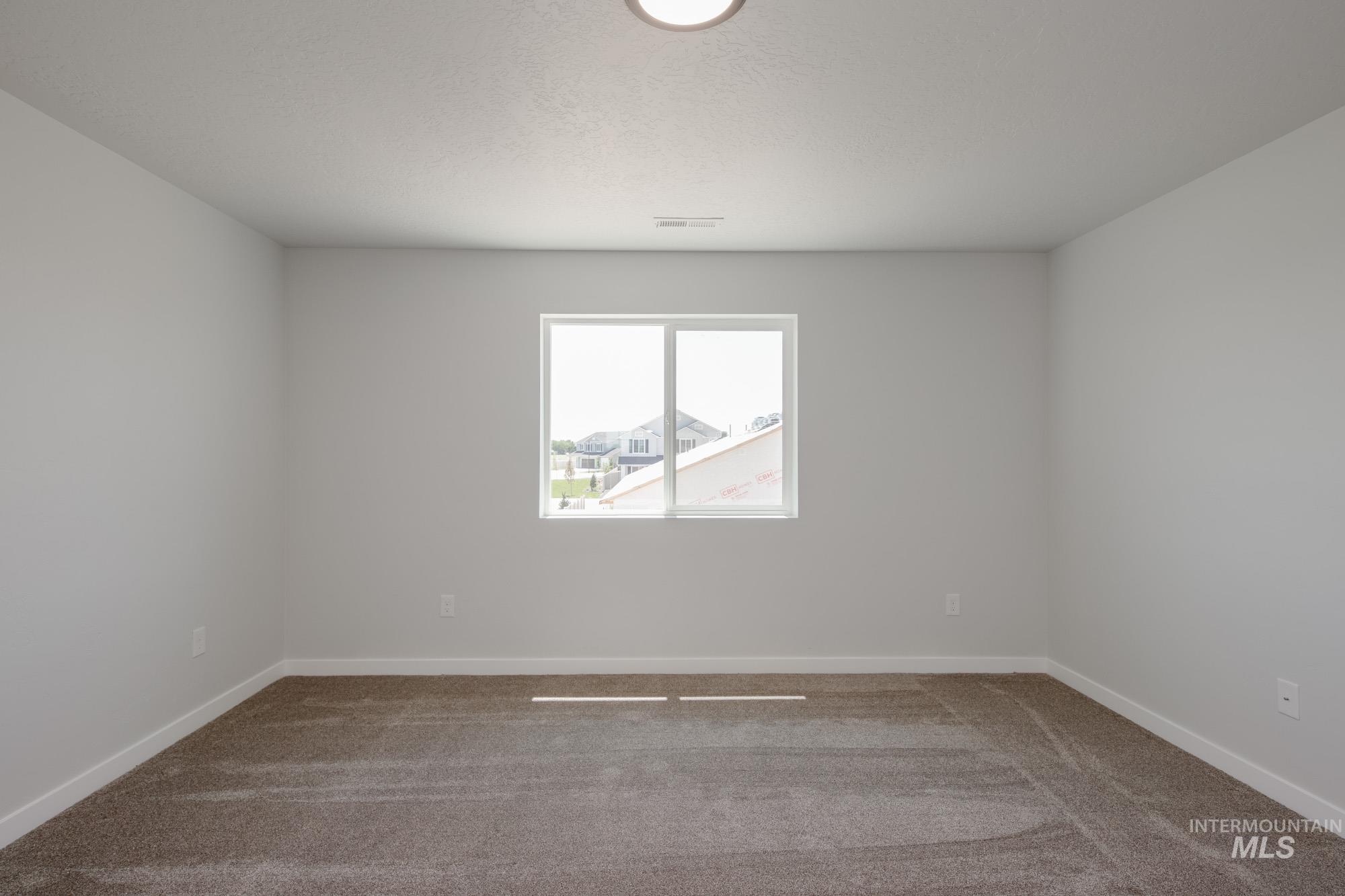 Empty room with carpet flooring and a textured ceiling