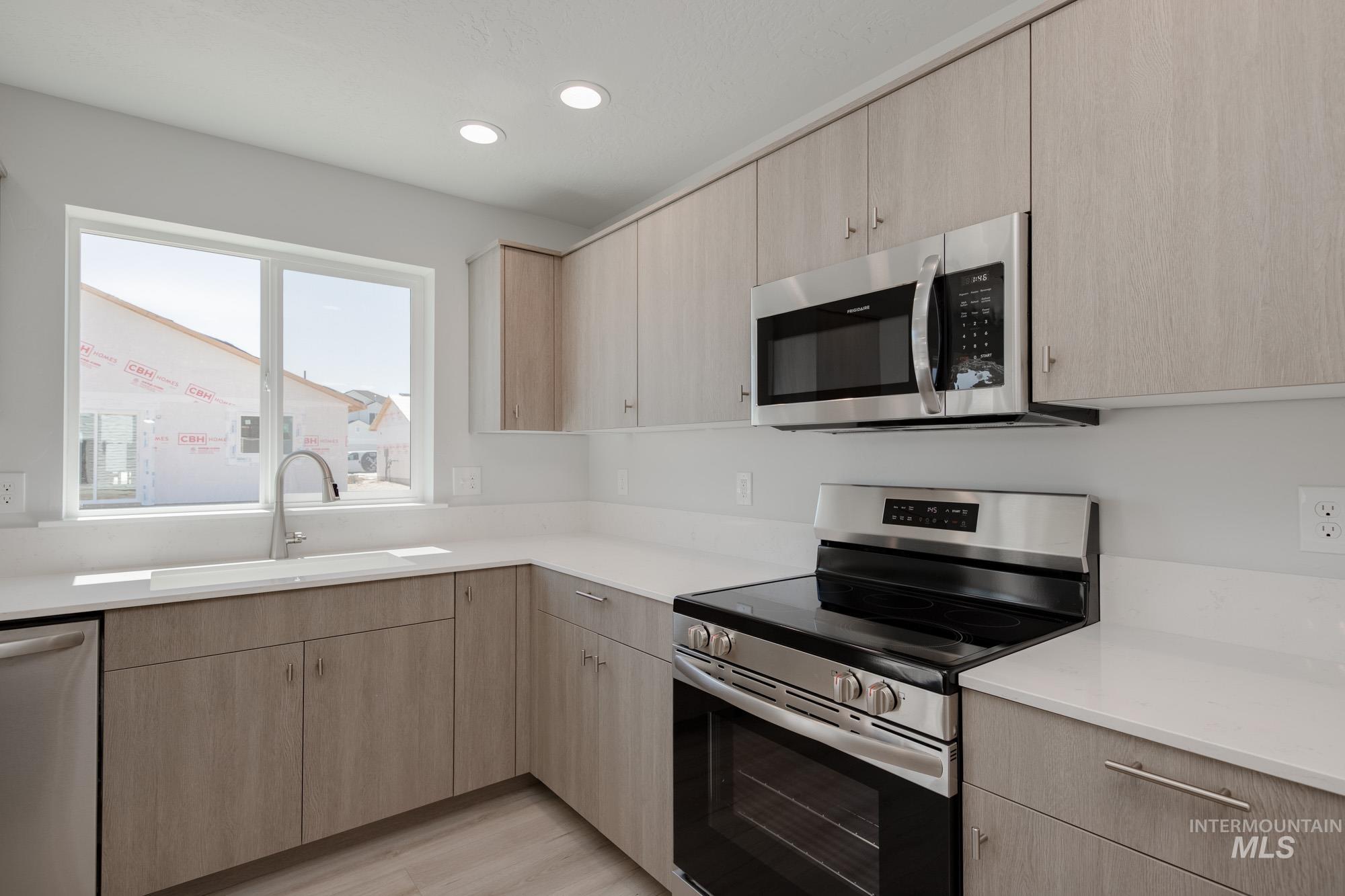 Kitchen featuring stainless steel appliances, light brown cabinetry, light countertops, and recessed lighting