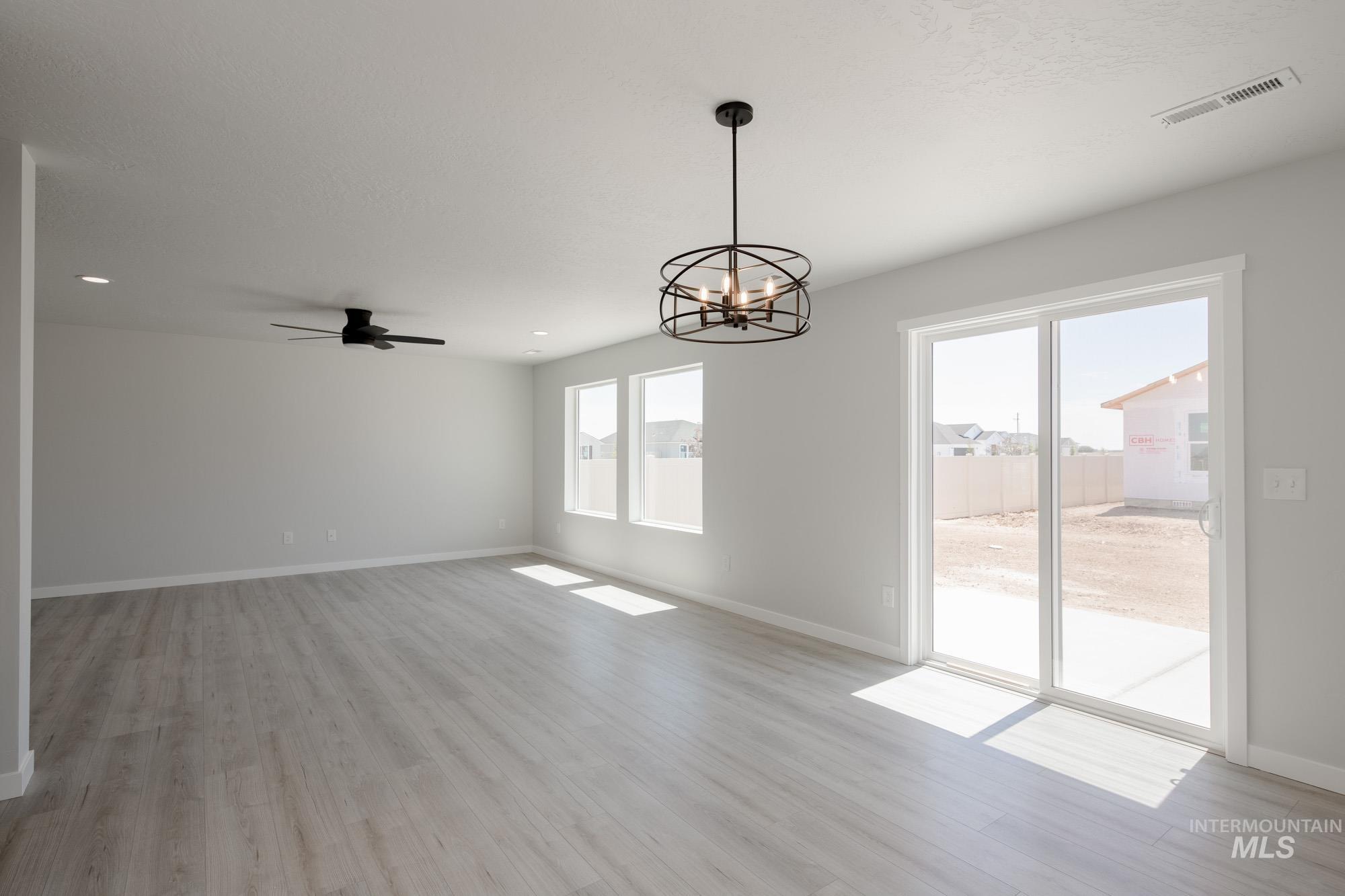 Unfurnished dining area with a chandelier, a ceiling fan, light wood finished floors, and recessed lighting