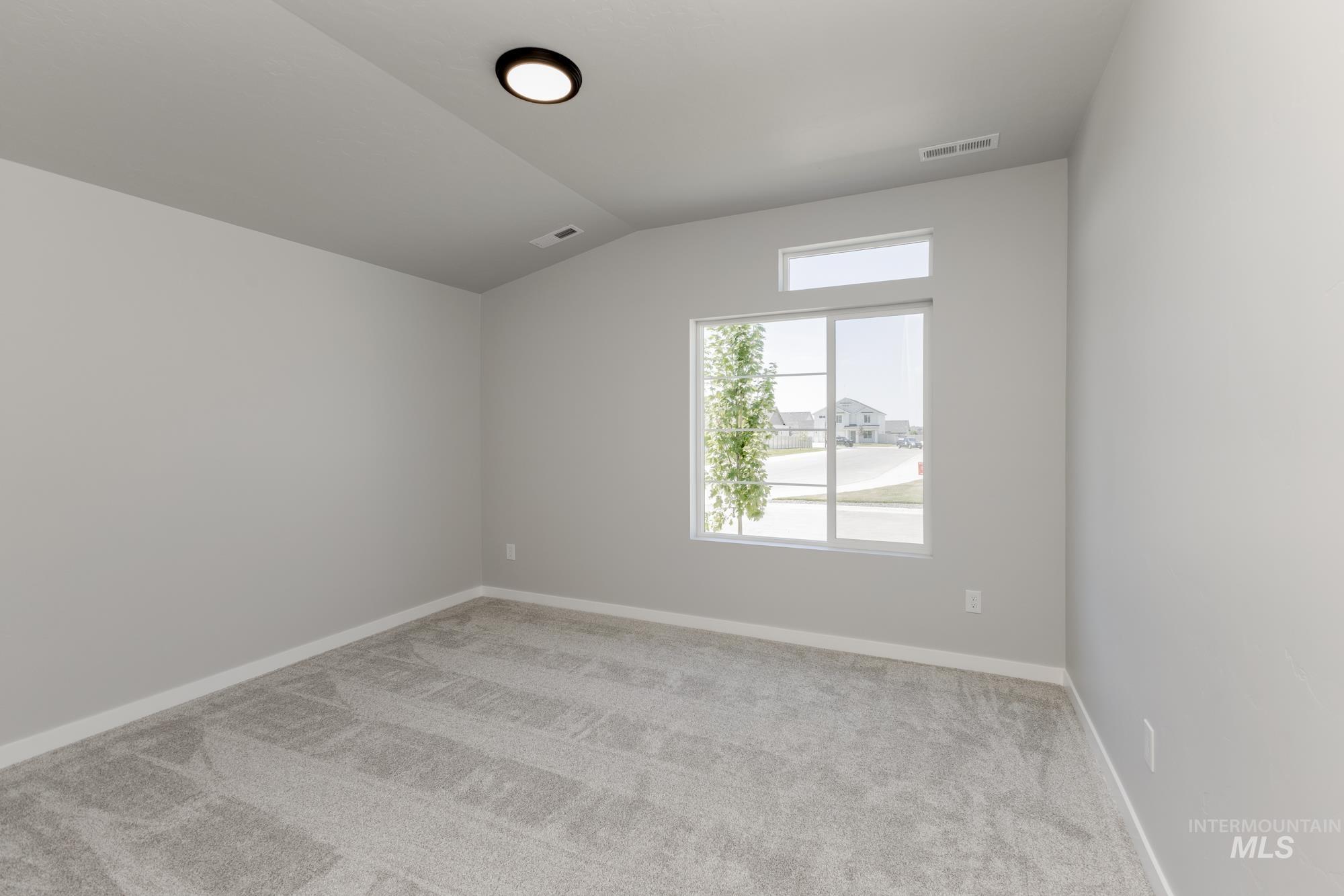 Spare room with carpet flooring and lofted ceiling