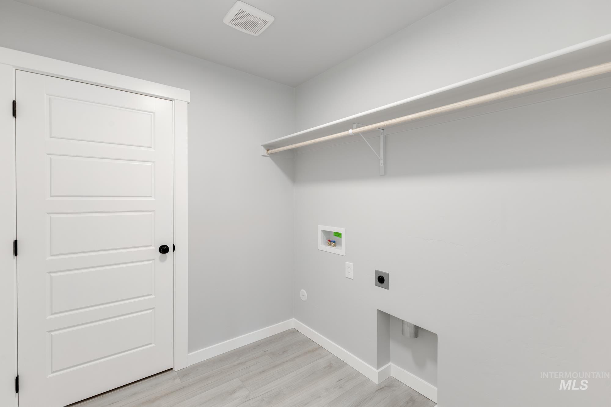 Laundry room featuring electric dryer hookup, washer hookup, and light wood finished floors