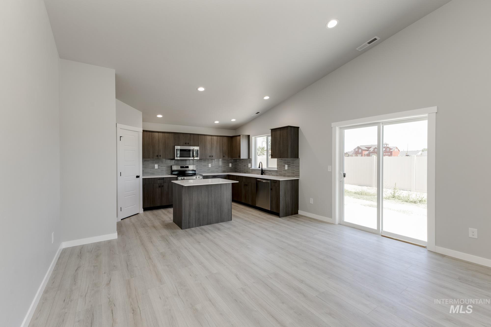 Kitchen with recessed lighting, decorative backsplash, a kitchen island, light countertops, and dark brown cabinetry